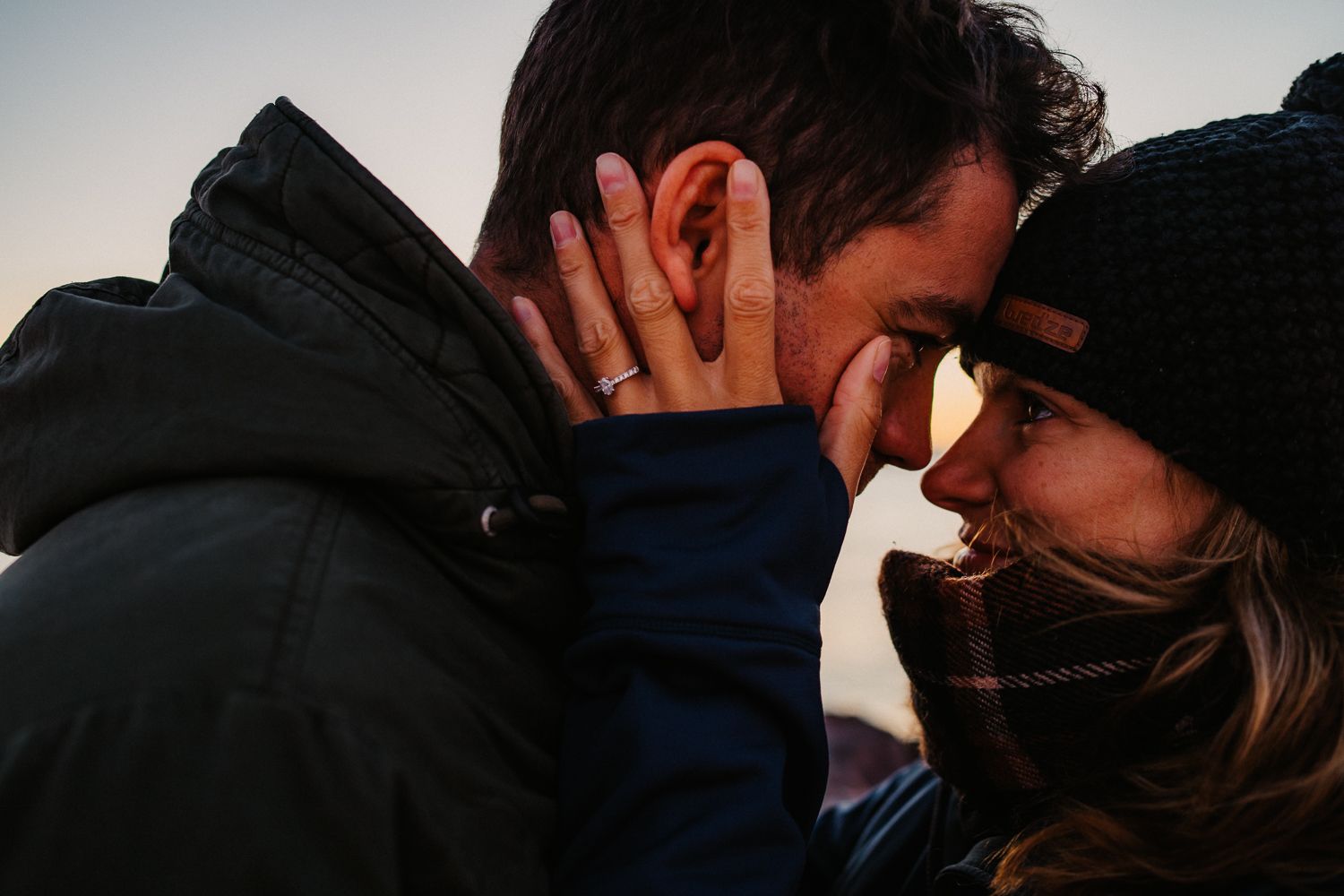 Photo of Matt & Jodie from everard films, looking into each others eyes whilst the sun is setting, wearing warm clothes
