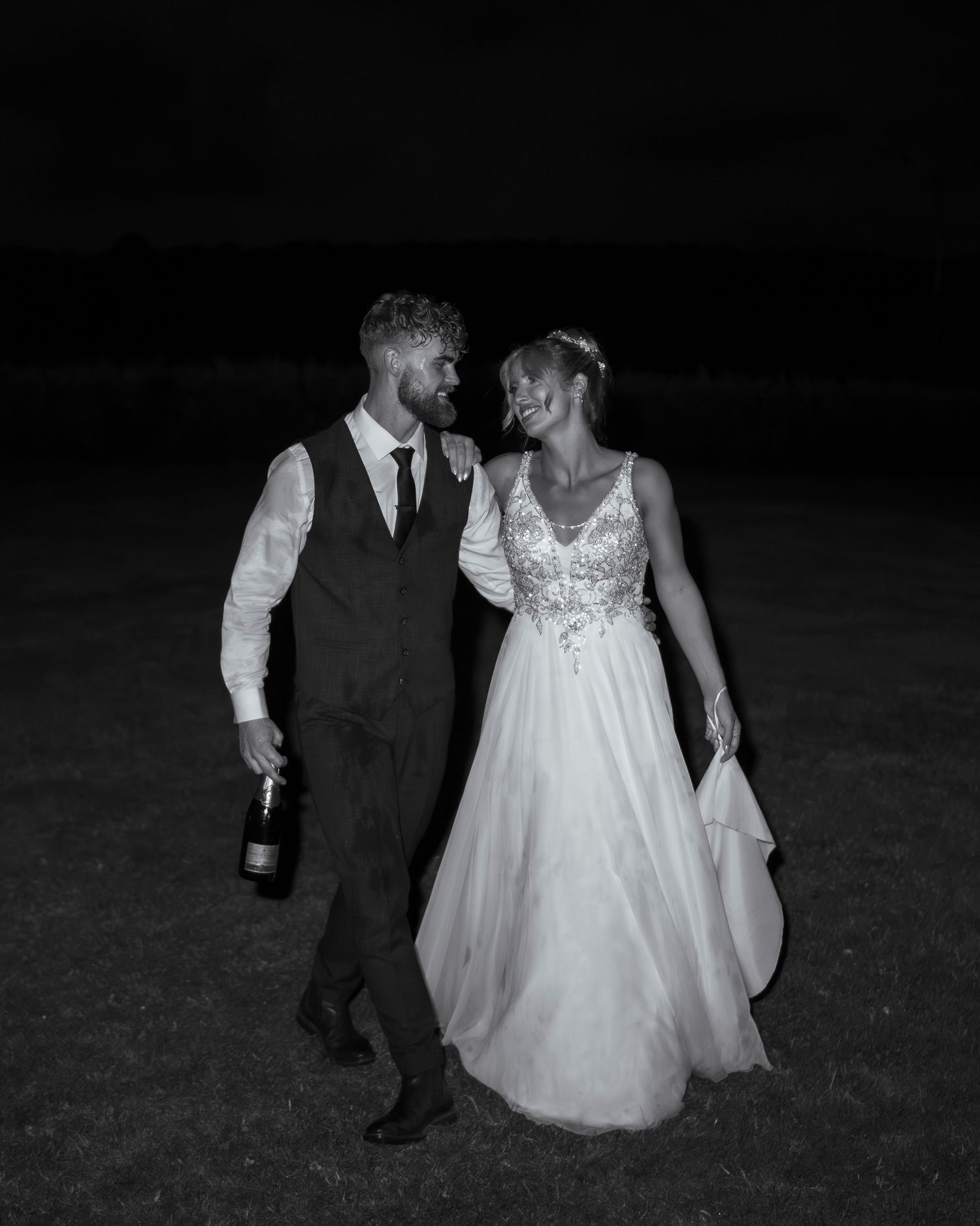Bride and groom celebrating with a bottle of champagne at their wedding in the UK.