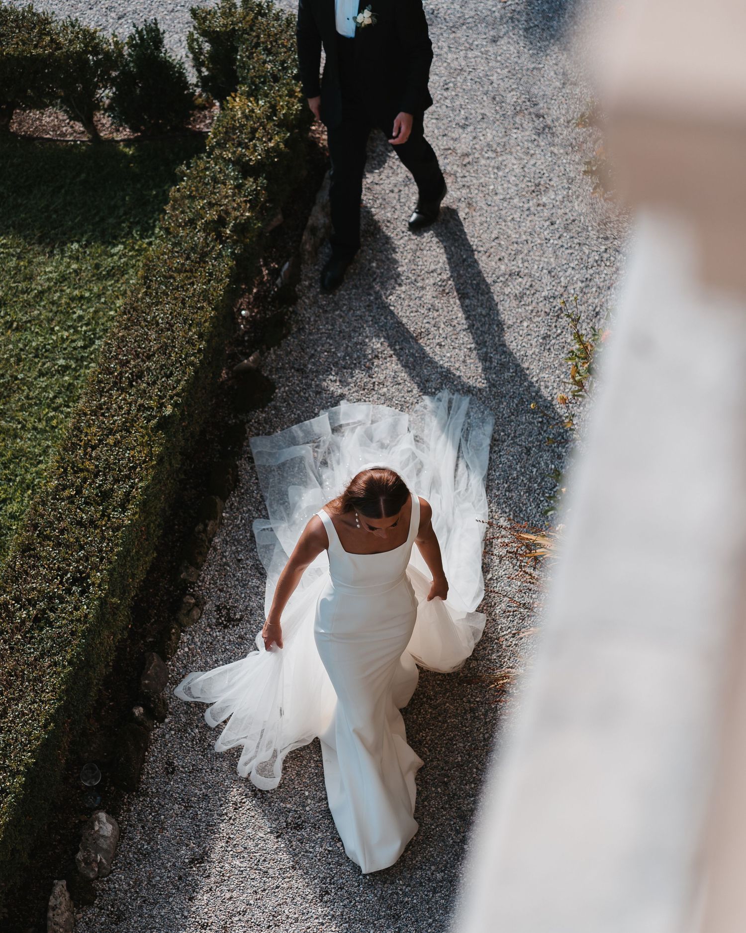 Bride captured from above showing all the beauty of her dress, her groom walks behind her at their Lake Garda Wedding
