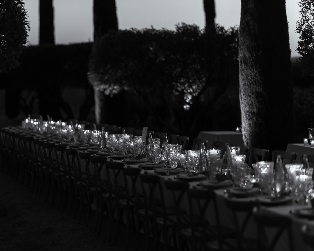 Black and white photo of long tables all set by candle light for the pre-wedding dinner in Provence, France