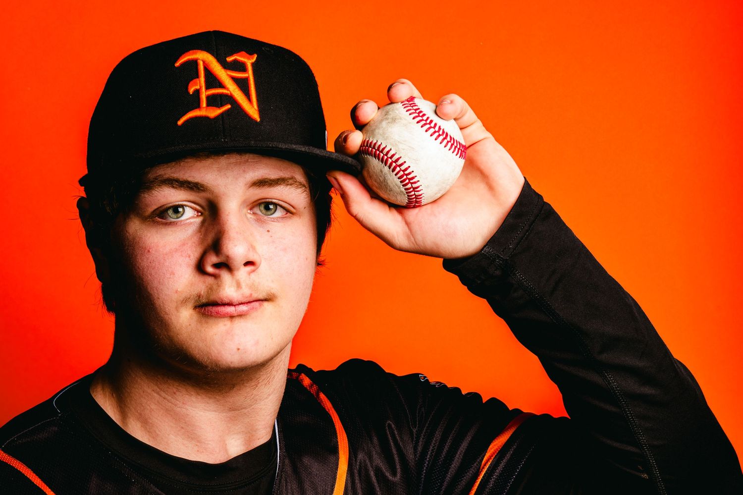 Baseball player wearing Detroit Tigers cap poses against vibrant orange background.