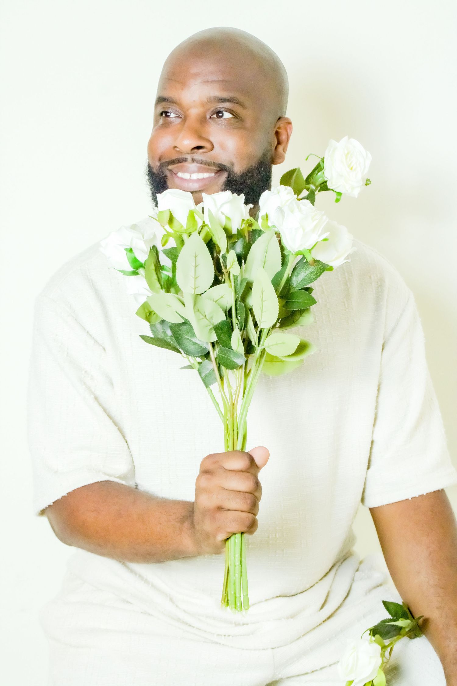 Studio photo featuring person holding fresh white flowers against bright background.