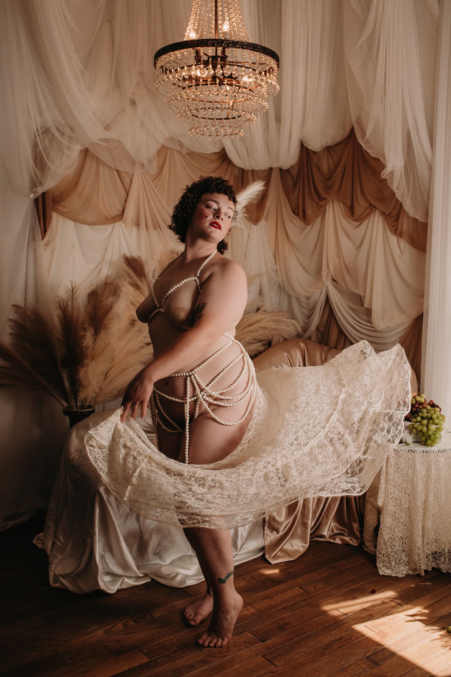 Vintage-inspired boudoir photo with crystal chandelier and draped fabric backdrop. Boudoir Photography Studio, Grand Rapids MI