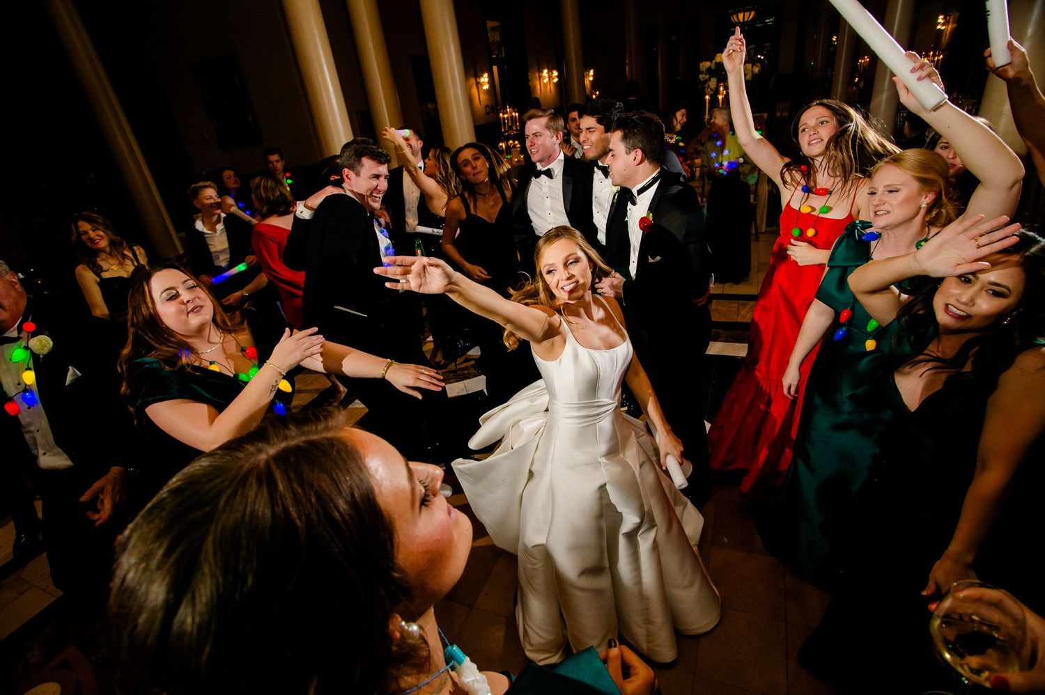 Bride dancing joyfully with guests at a lively wedding reception party.