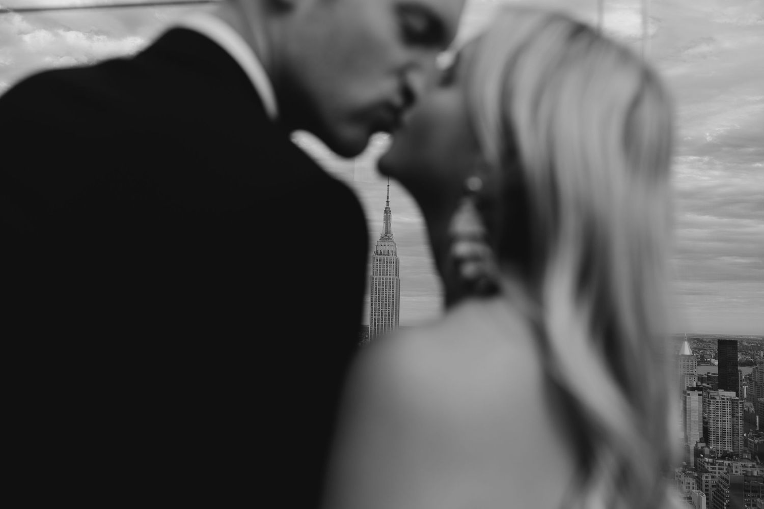 Black and white images show someone kissing passionately against a blurry background with soft lighting.