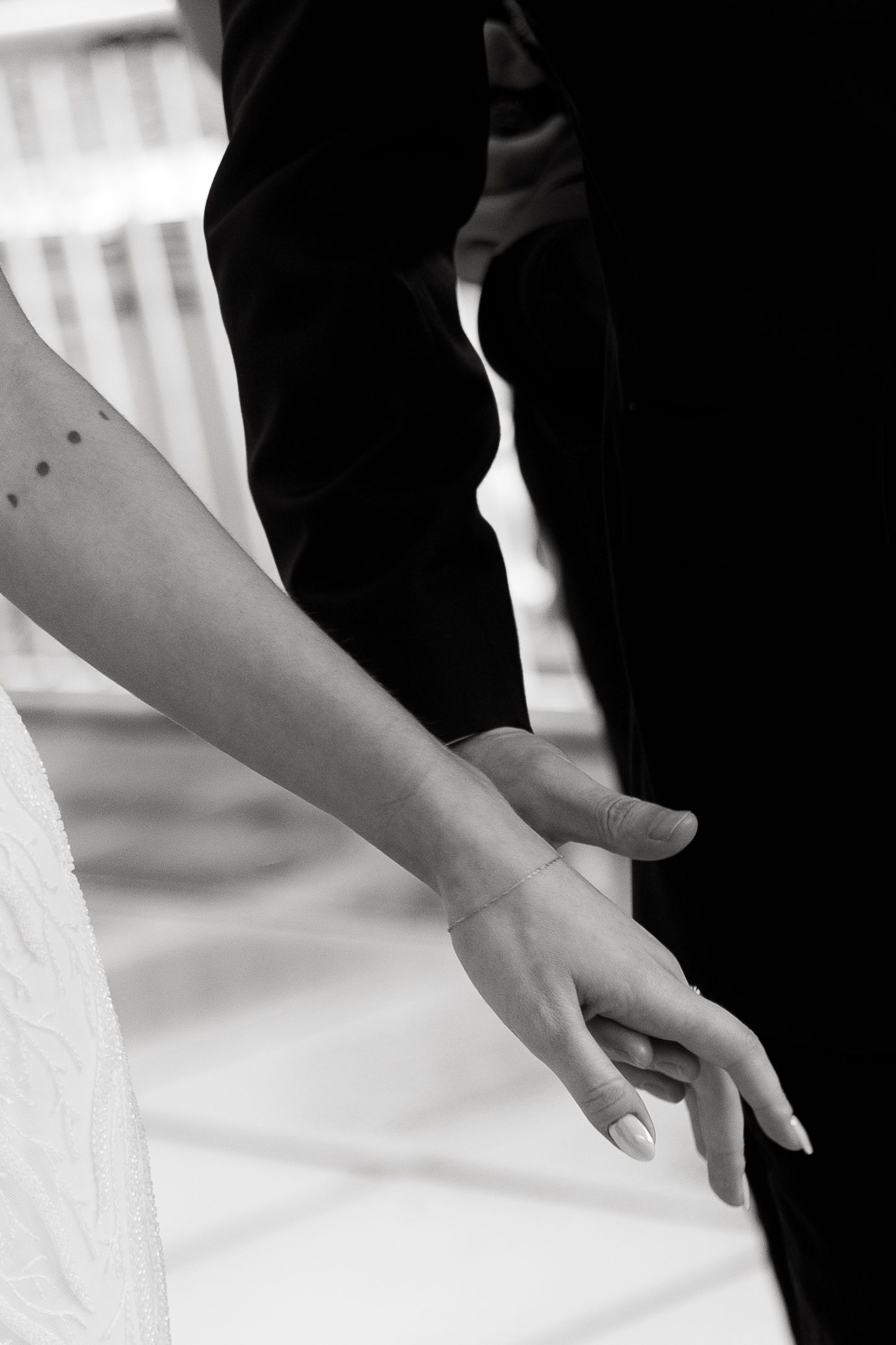 Close up view of a person's hand folding clean white linens against a bright background.