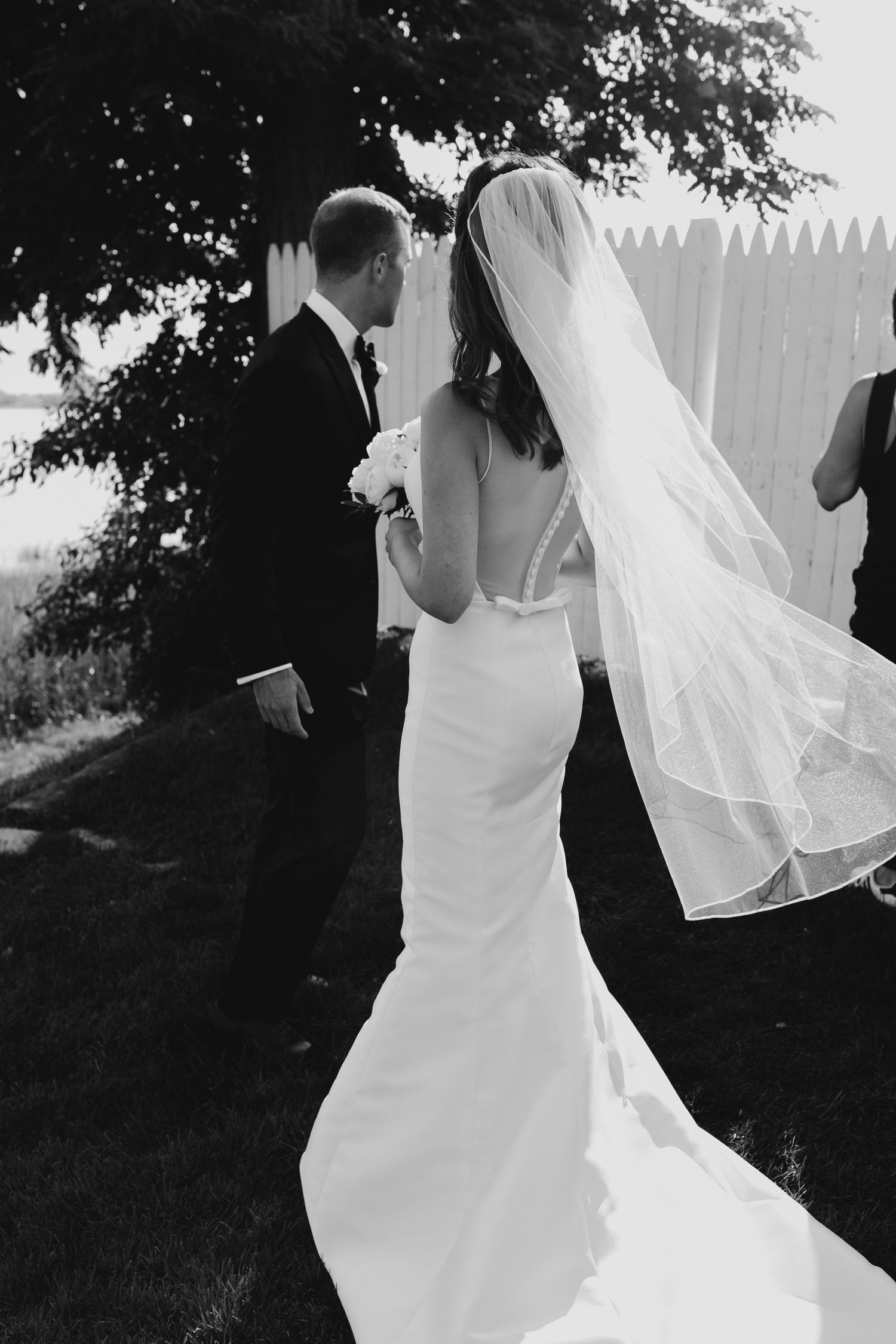 Romantic wedding scene showing bride in flowing white dress twirling in sunlit garden setting.