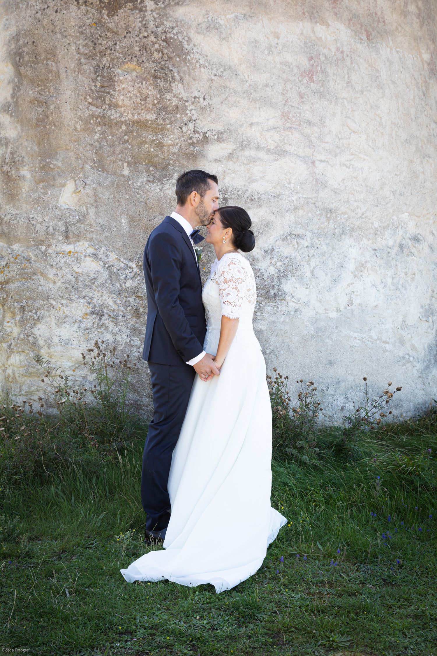 bröllopsfotograf emeraldWeddings Gotland sommarbröllop i Djupvik bröllopsporträttfotografering brudpar håller händer kyss på pannan kalksten