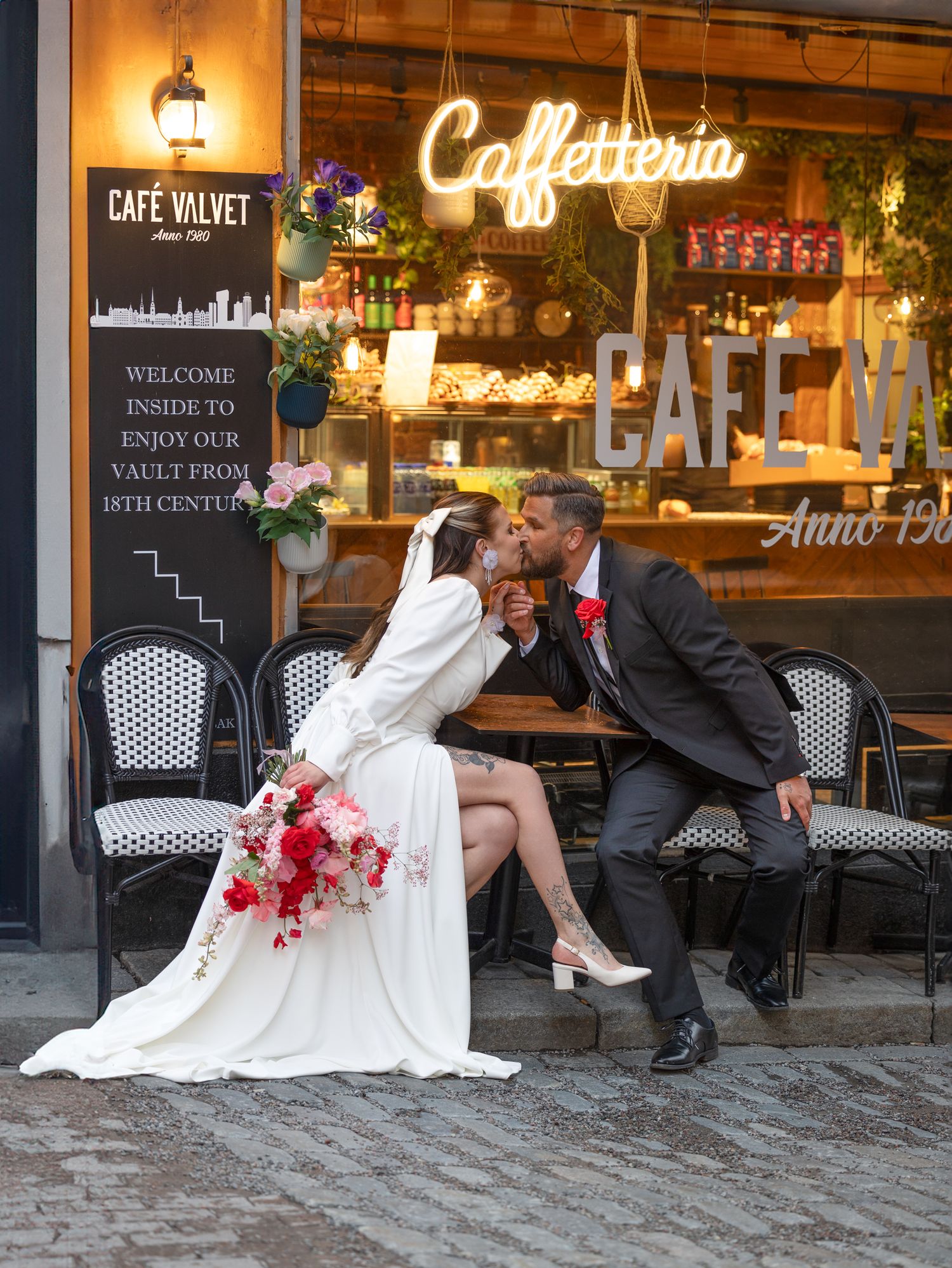 Kyssande brudpar utanför kaféfönster i gamla stan stockholm bröllopsporträtt av EmeraldWeddingsbröllopsfotograf bröllop i stadsmiljö