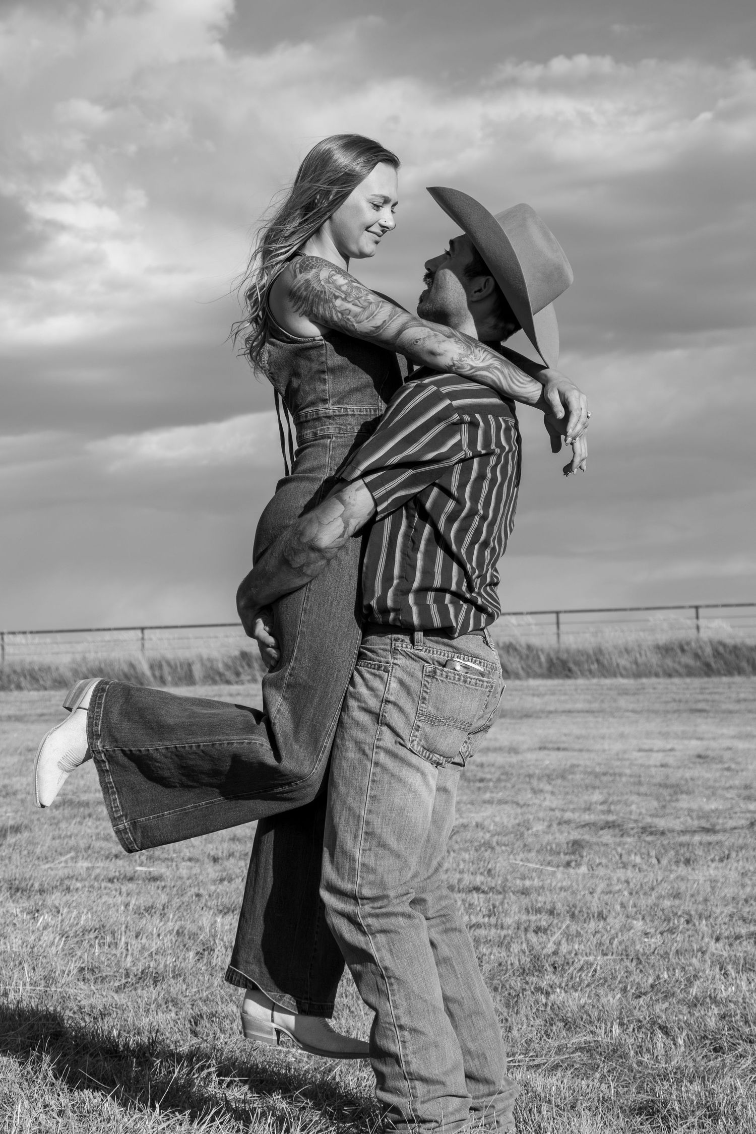 Black and white photo sequence showing a playful couple spinning and embracing in an open field with cloudy skies.