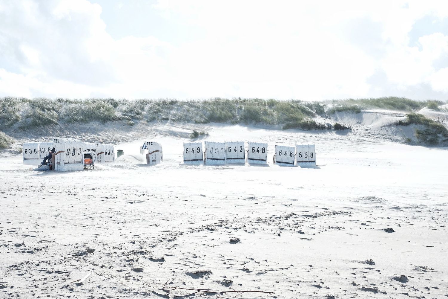 Des cabines de plage en osier alignées sur le sable blanc d'une plage ensoleillée sur l'ile de Spiekeroog en Allemagne par Jérémie Botte.