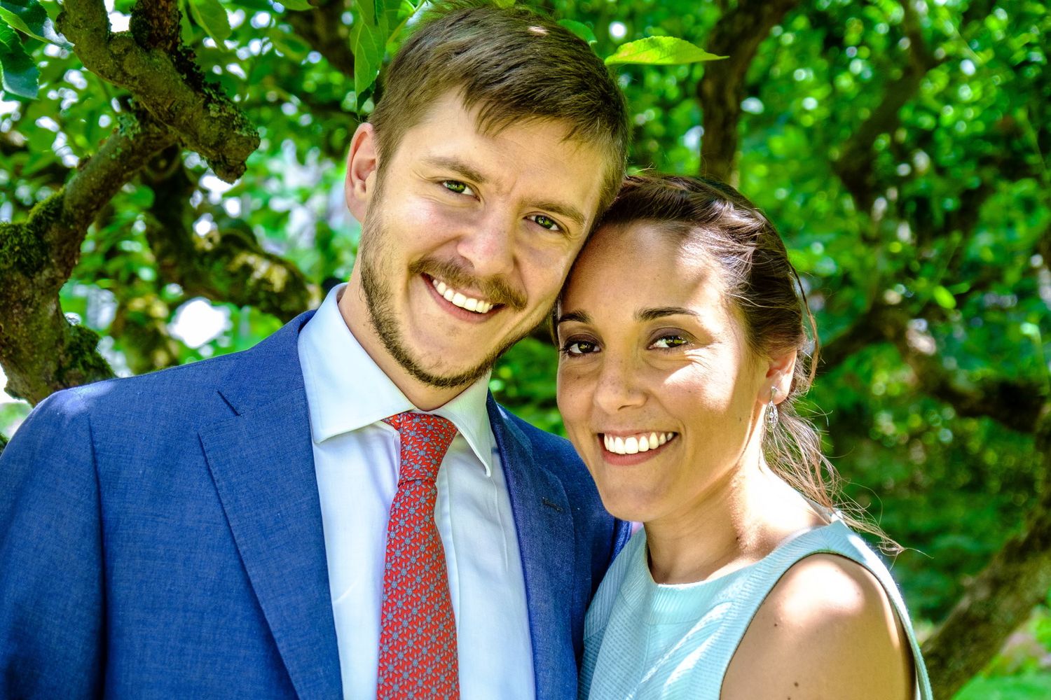 Le portrait complice et souriant d'un jeune couple de mariés posant tête contre tête, par Jérémie Botte.