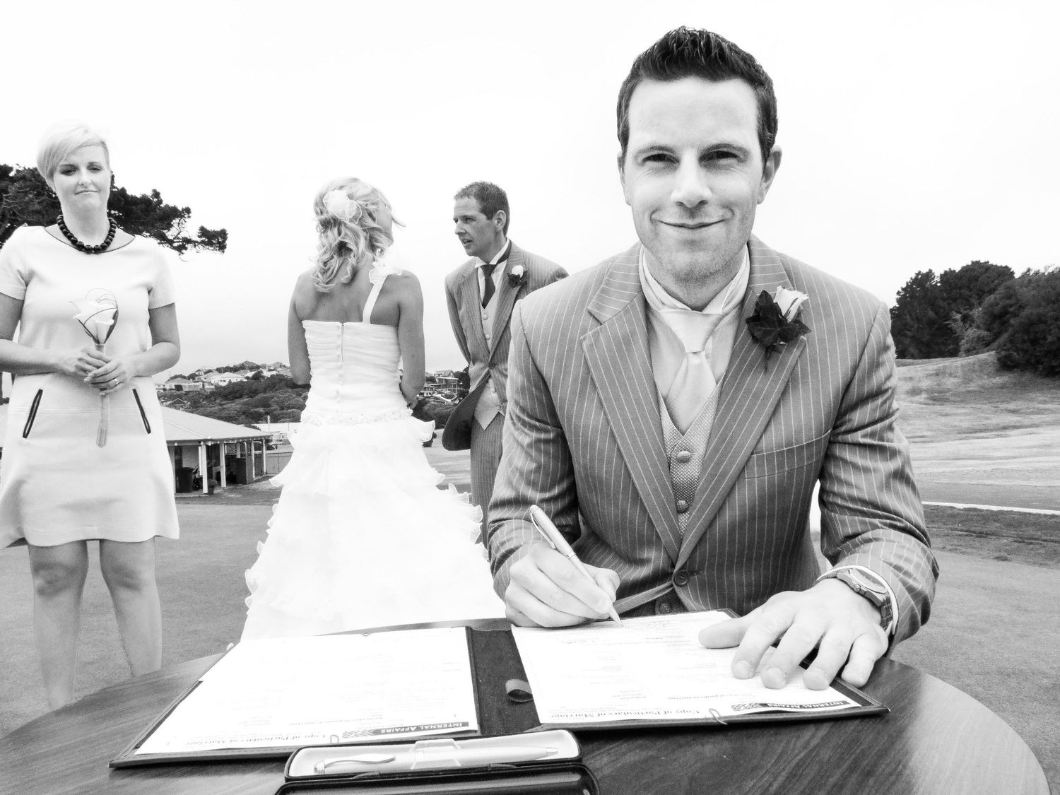 Photo en noir et blanc du best mate tout sourire qui signe les registres officiels, par Jérémie Botte.