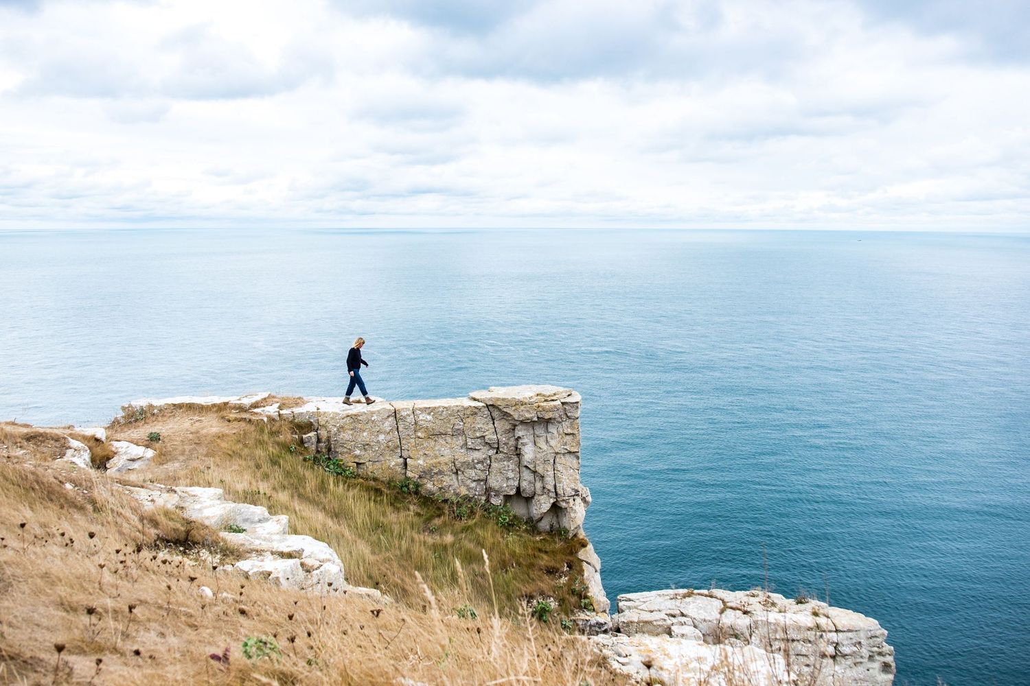 Photo de voyage au Royaume-Uni montrant la silhouette d'une femme marchant au bord d'une falaise de craie blanche par Jérémie Botte.