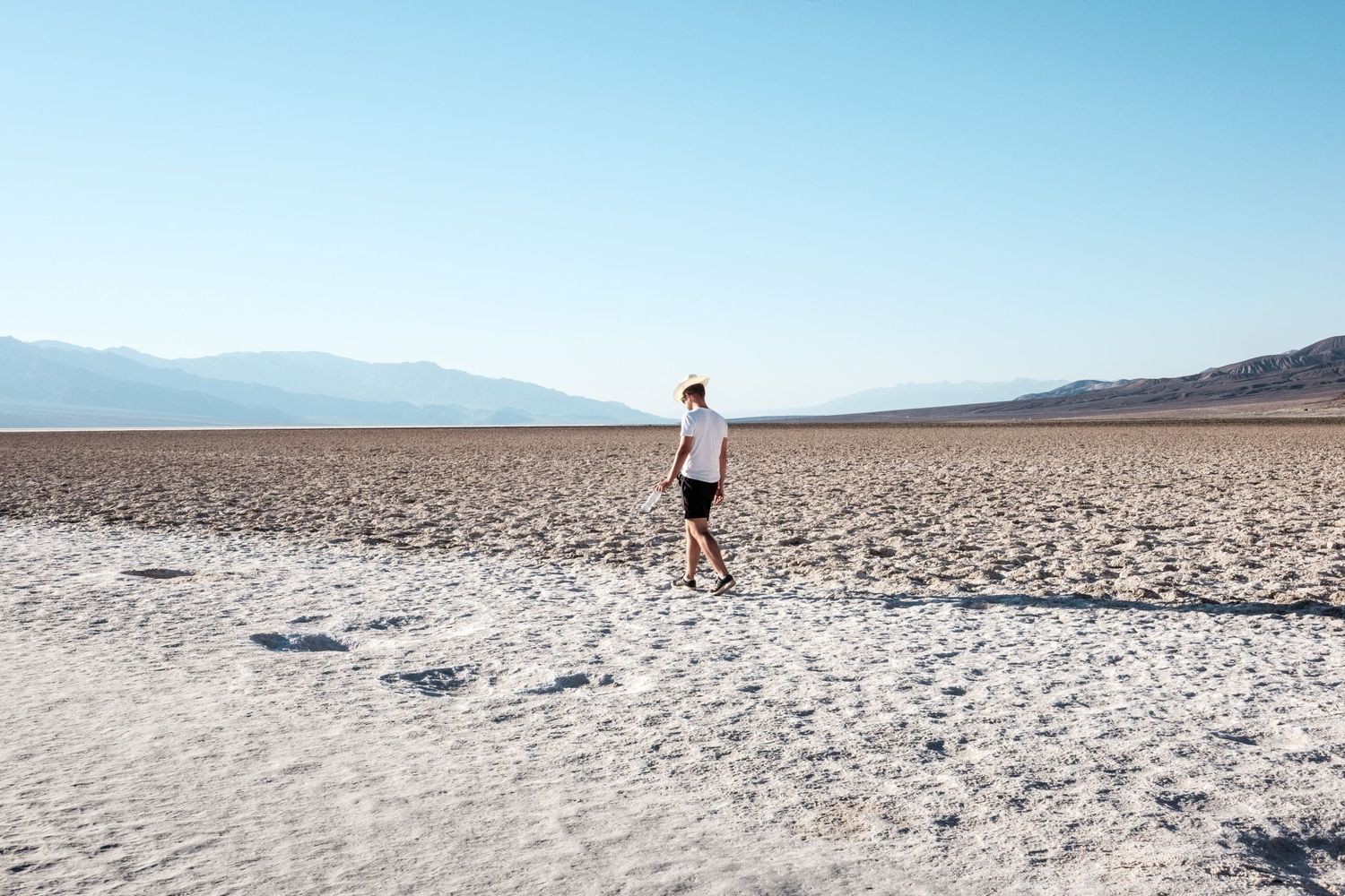 Une personne marchant seule sur l'immensité de sel blanc de Badwater Basin dans la vallée de la Mort, par Jérémie Botte.