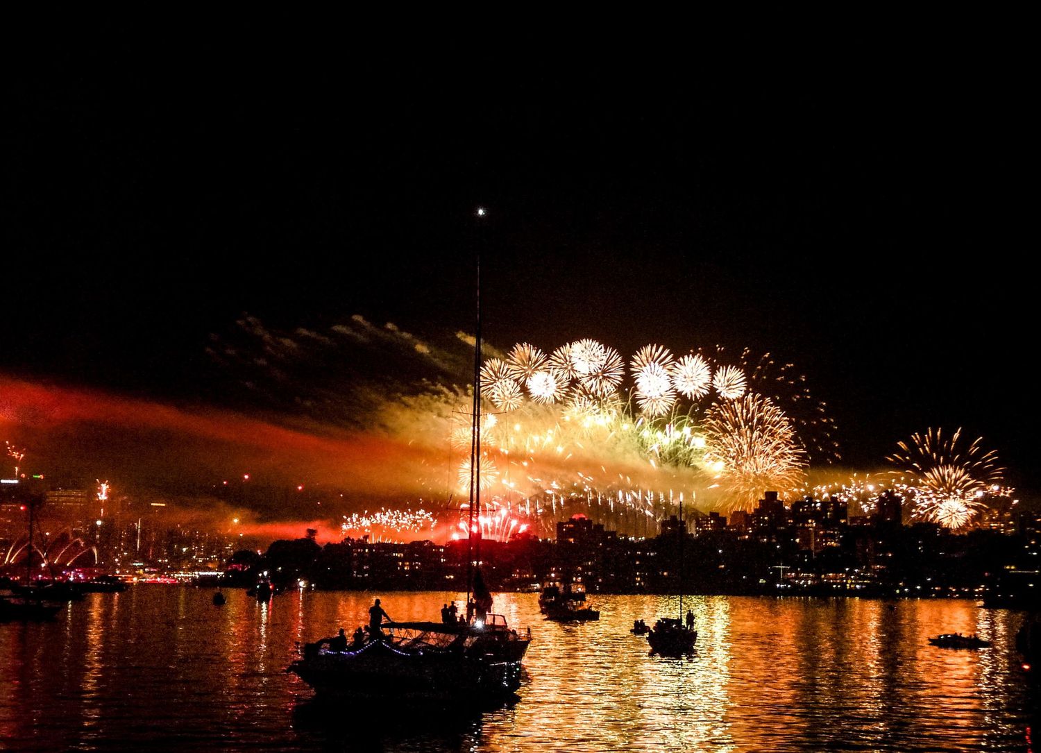 Feu d'artifice spectaculaire dans la nuit du nouvel an dans la baie de Sydney, illuminant le ciel et les silhouettes de bateaux, par J Botte