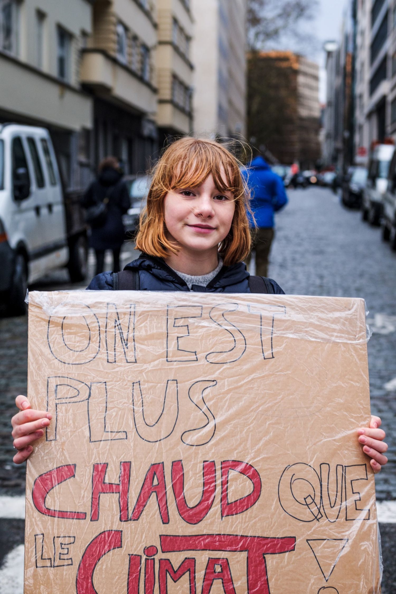 Une jeune fille rousse tient une pancarte de manifestation pour le climat dans la rue par Jérémie Botte.