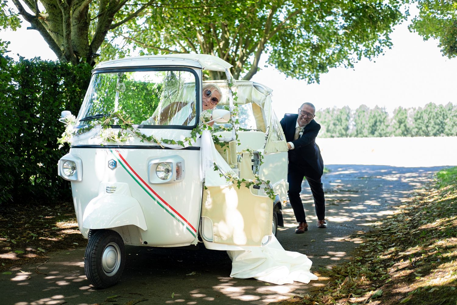 Photographie de mariage en exterieur de jour des deux mariés s'amusant dans une voiturette italienne par le photographe Jérémie Botte.