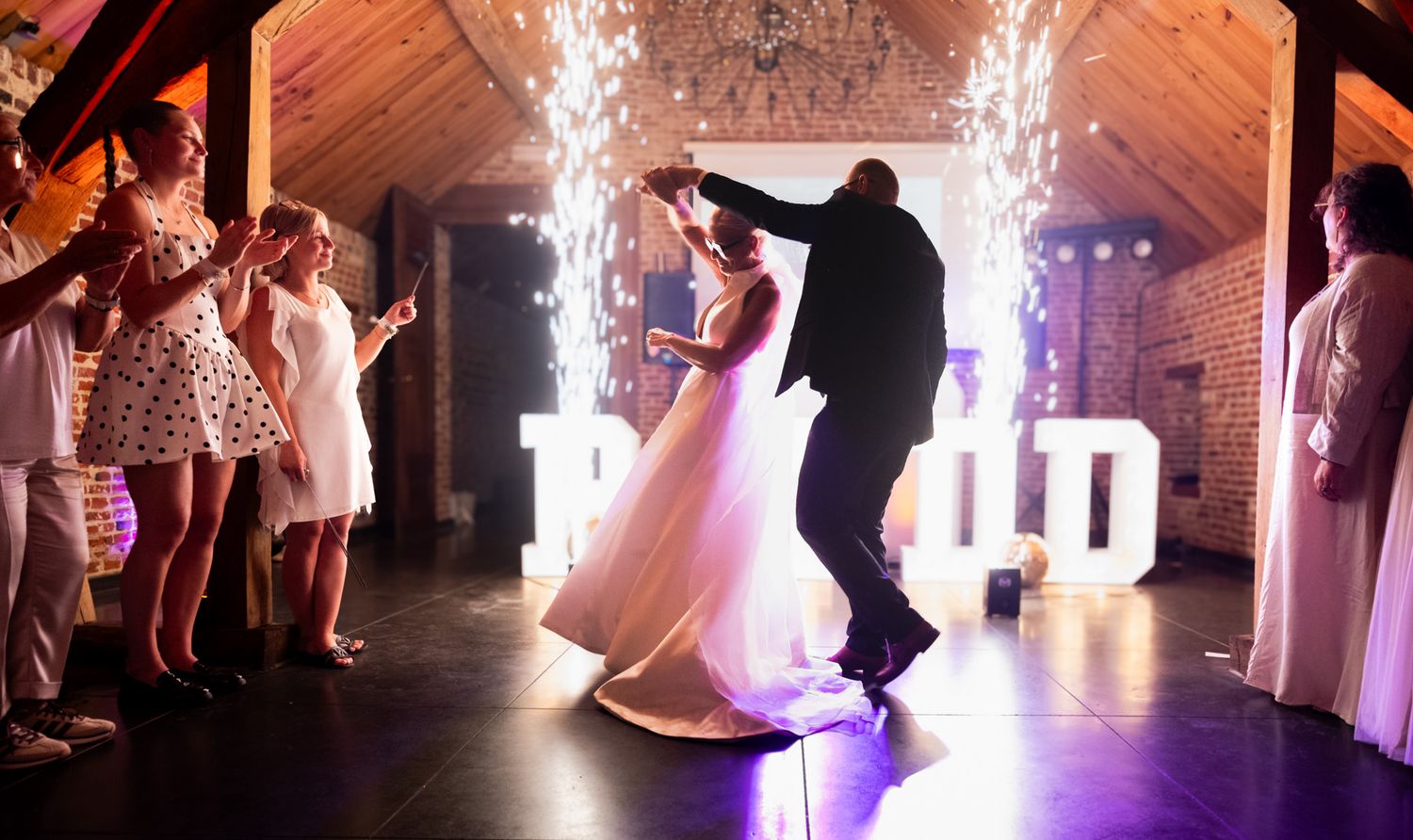 Photographie de mariage sur le dancefloor de nuit avec des étincelles froides en intérieur par le photographe professionel Jérémie Botte.