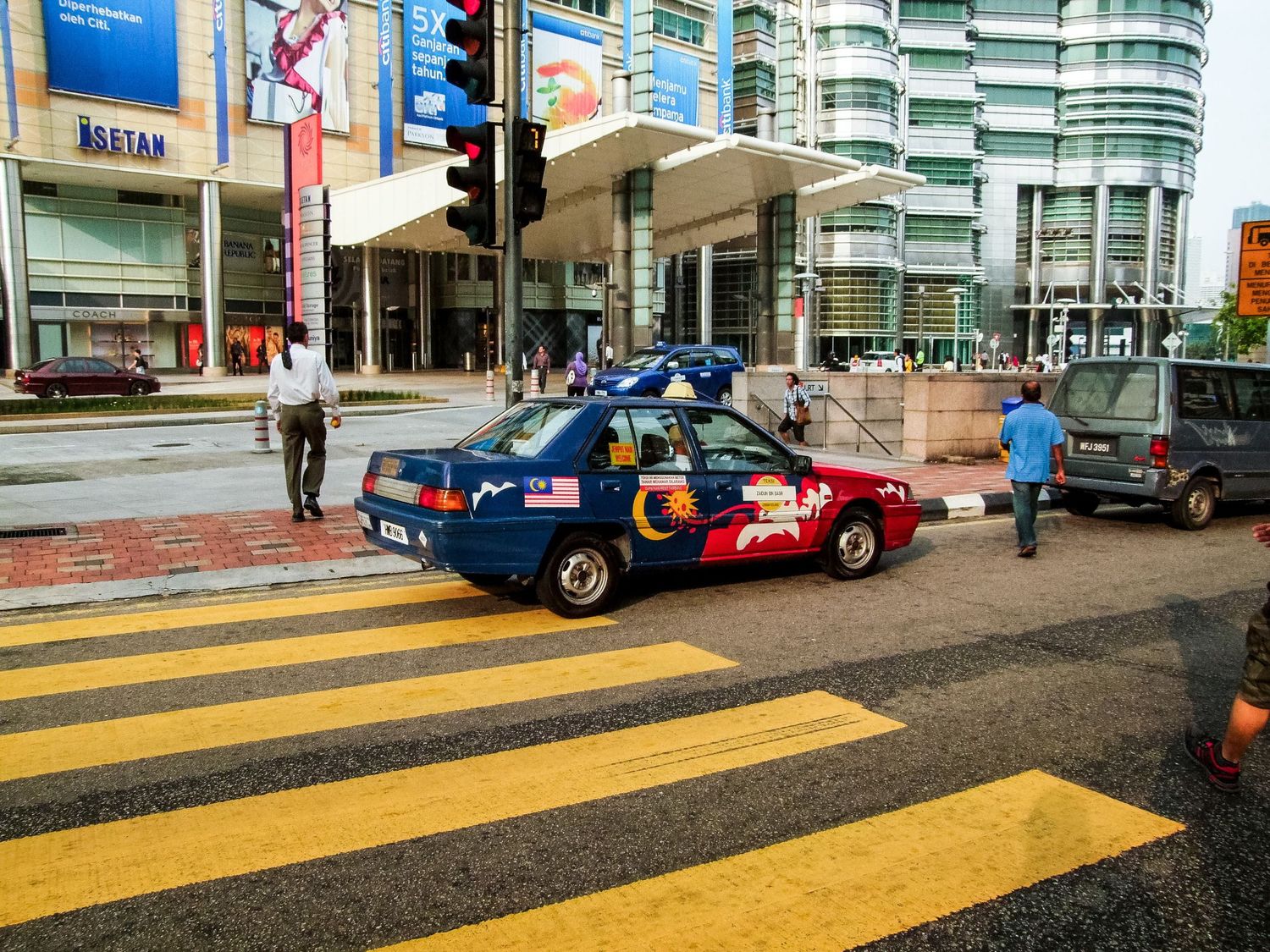 Une voiture décorée aux couleurs du drapeau malaisien traversant un passage piéton à Kuala Lumpur, par Jérémie Botte.