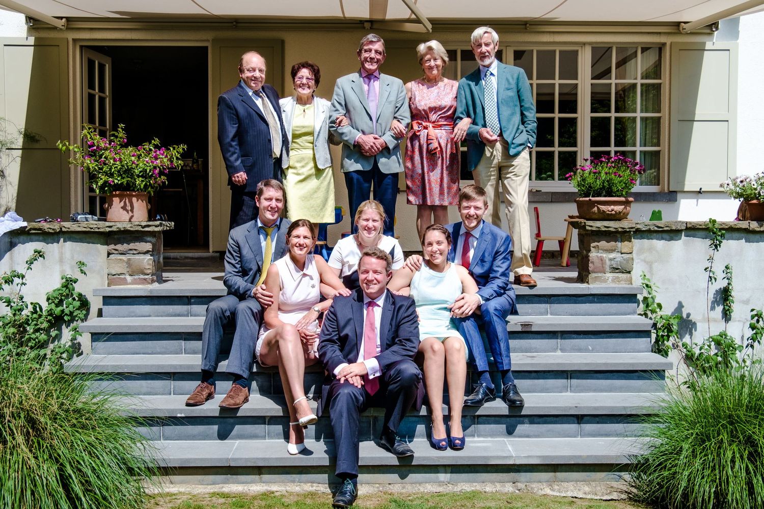 Une photo de famille élégamment vêtue, posant tout sourire sur les marches de la terrasse extérieure d'une maison, photo de Jérémie Botte.