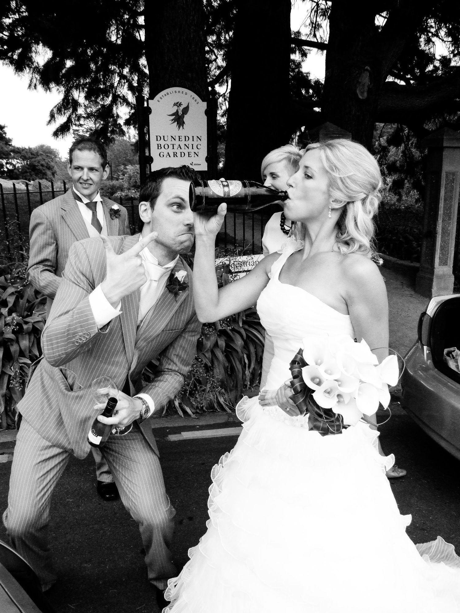 Photo humoristique en noir et blanc de la mariée buvant à la bouteille devant le Dunedin Botanic Garden, par Jérémie Botte.