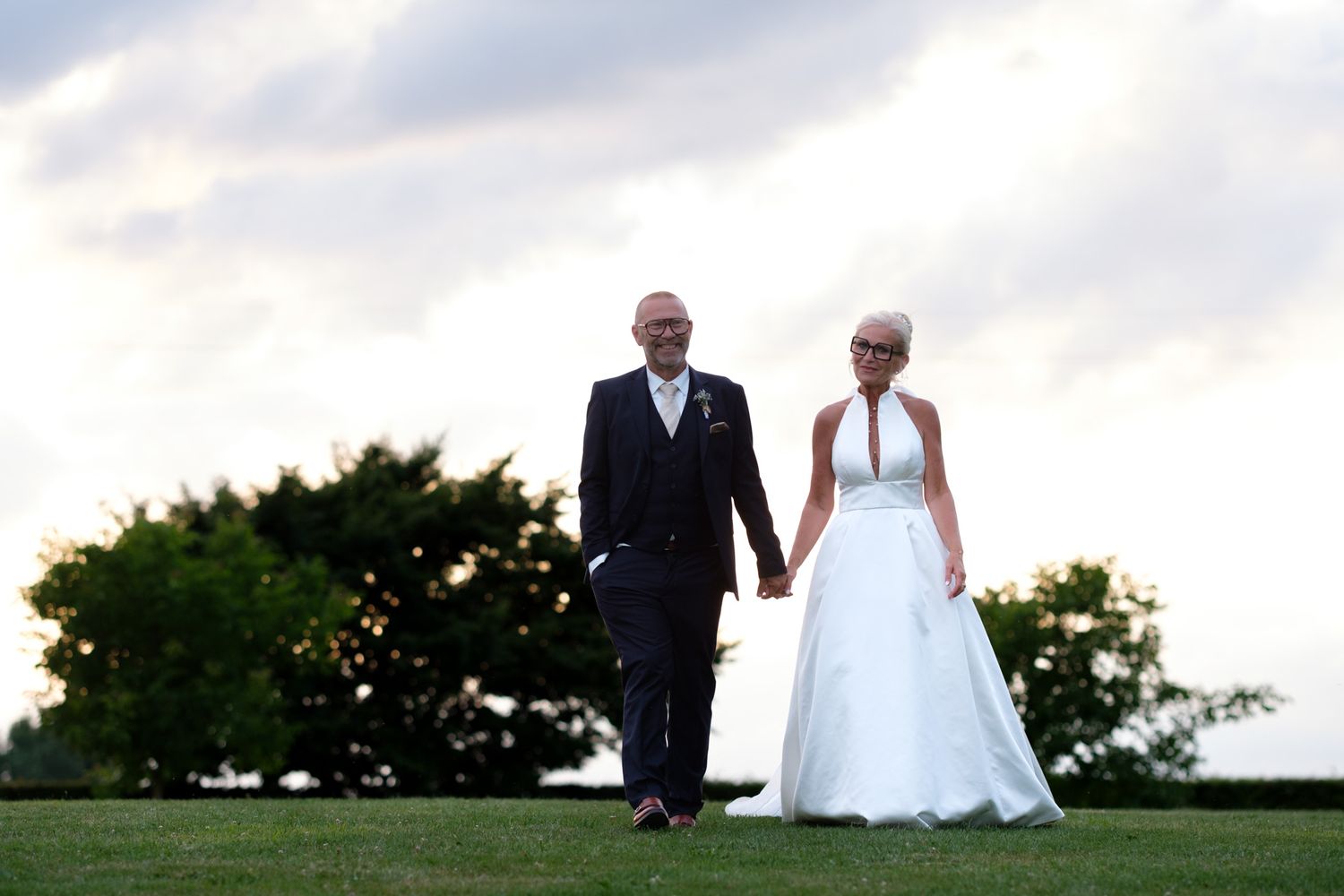 Photographie de mariage durant la Goldent Hour de deux mariés main dans la main par le photographe professionel Jérémie Botte.
