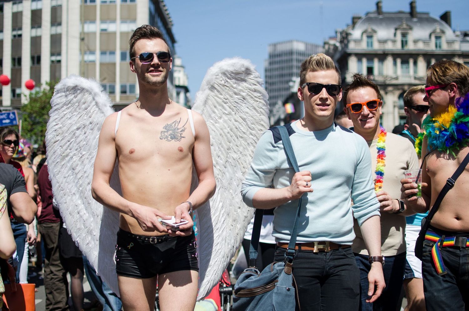Deux hommes défilent à la Gay Pride, l'un d'eux torse nu porte de grandes ailes d'ange blanches par Jérémie Botte.