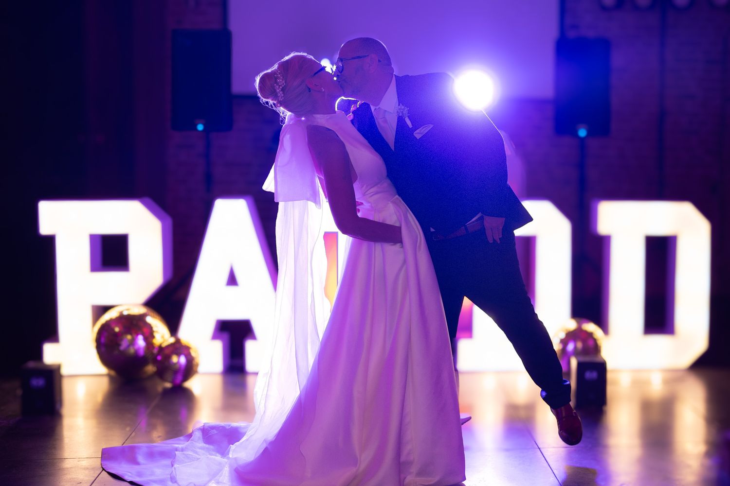 Photographie de mariage de mariés s'embrassant sur le dancefloor en intérieur de nuit par le photographe professionel Jérémie Botte.