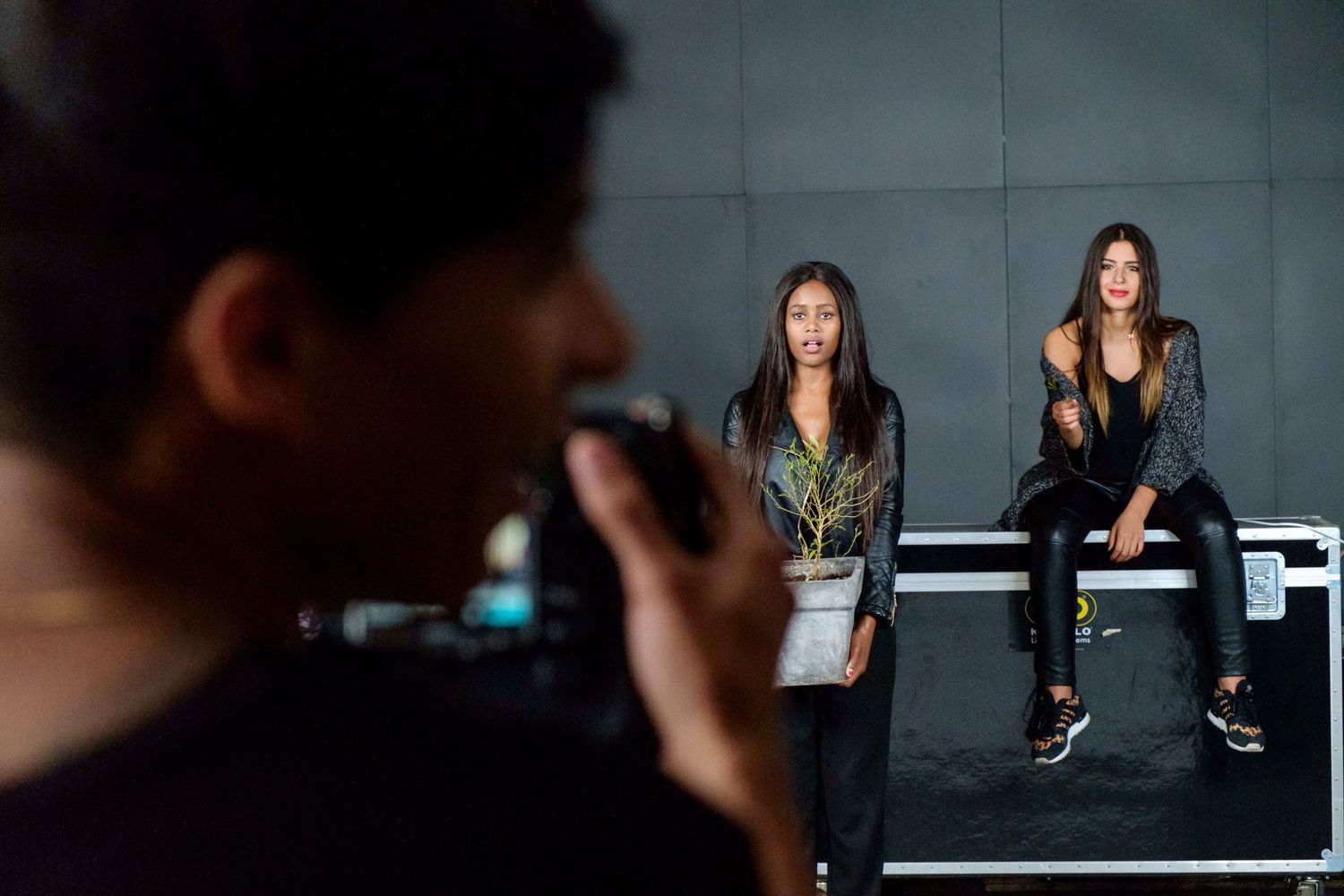 Deux jeunes femmes posent en studio devant un photographe vu de dos en premier plan flou par Jérémie Botte.