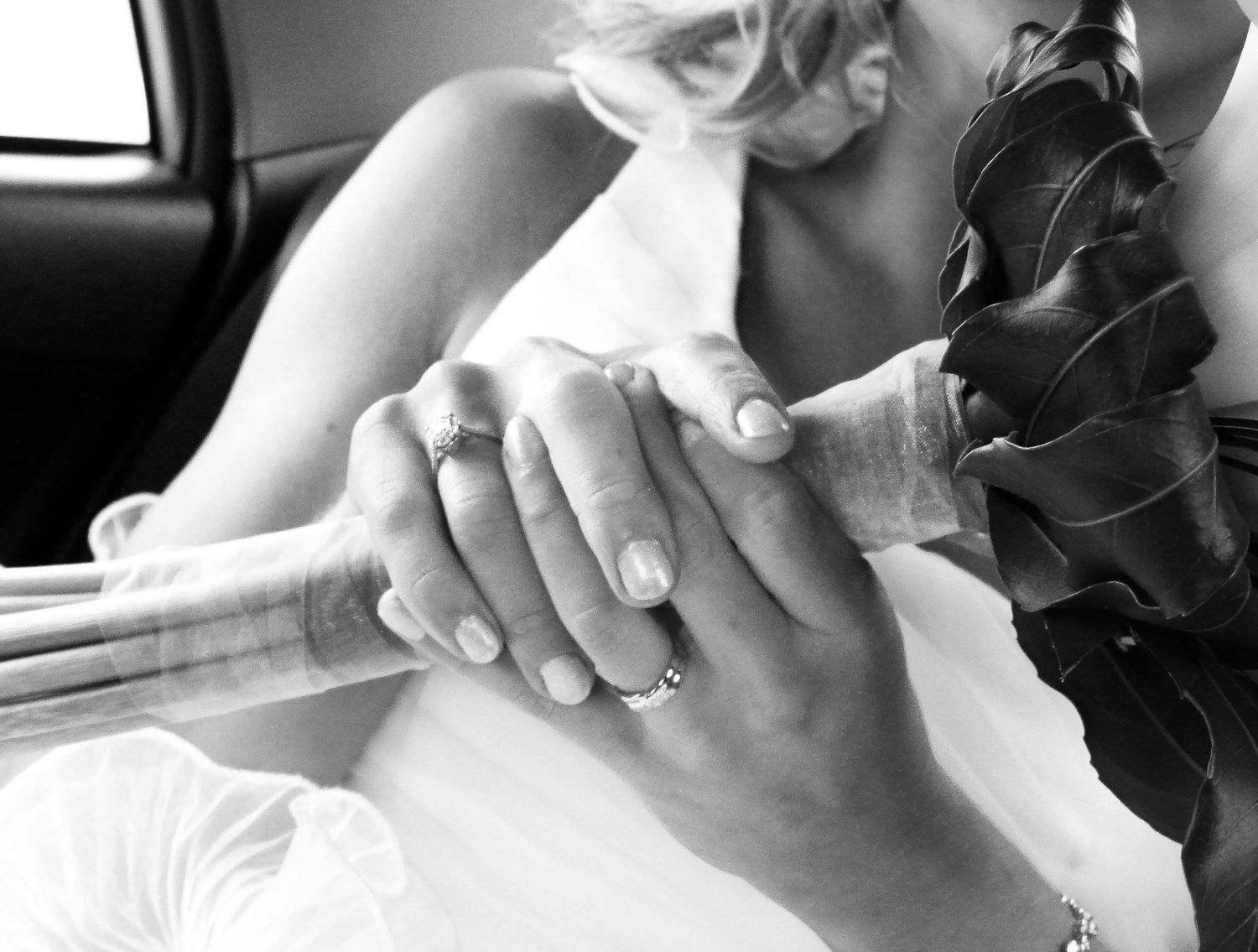 Gros plan sur les mains d'une mariée tenant un bouquet de fleurs noires, par Jérémie Botte.