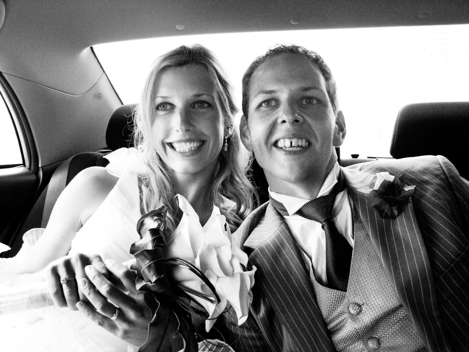 Couple de mariés souriant ensemble à l'arrière d'une voiture, par Jérémie Botte.