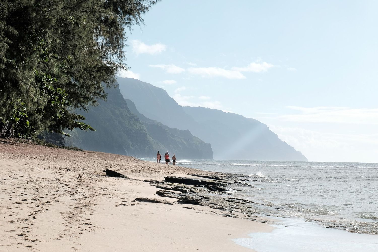 Photographie de voyage aux États-Unis de promeneurs dans la réserve Na Pali sur une plage sauvage bordée de montagnes par Jérémie Botte.