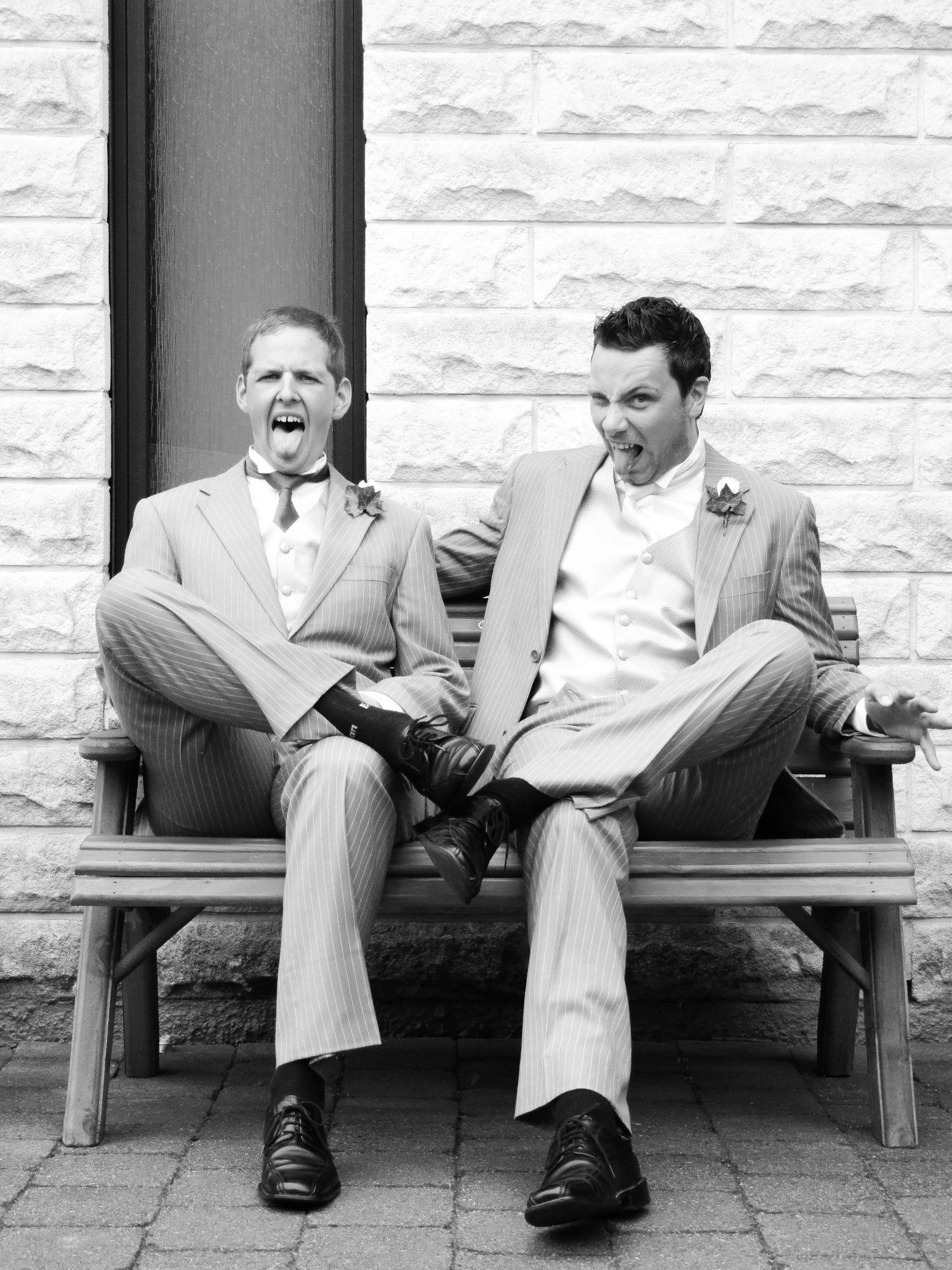 Deux hommes en costume posant sur un banc en briques, par Jérémie Botte.