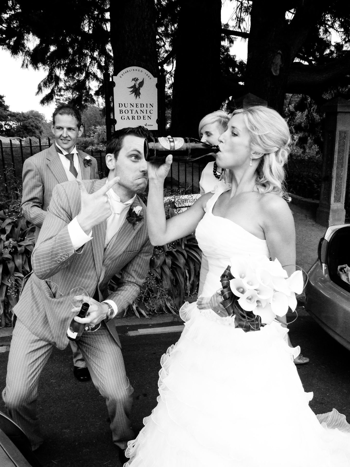 Photo humoristique en noir et blanc de la mariée buvant à la bouteille devant le Dunedin Botanic Garden, par Jérémie Botte.
