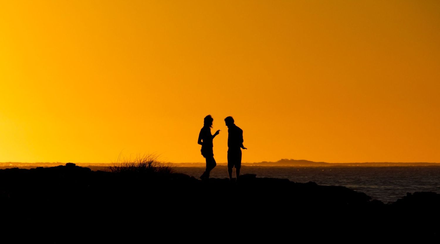 Photo de voyage dans le Western Australia montrant la silhouette de deux personnes face à un coucher de soleil orange par Jérémie Botte.
