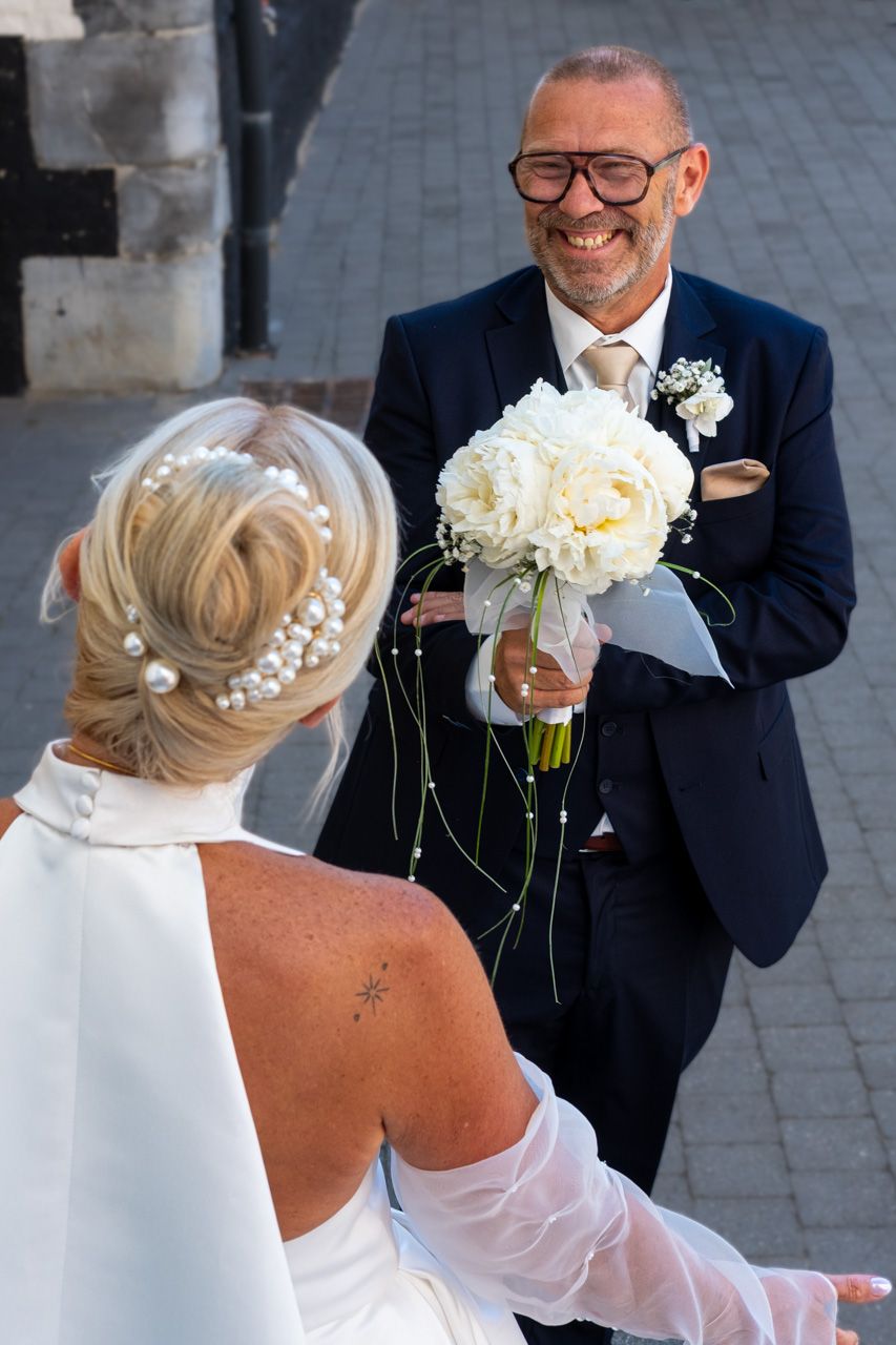 Photographie de mariage en exterieur des deux futurs mariés durant découverte de la robe de la mariée par le photographe Jérémie Botte.