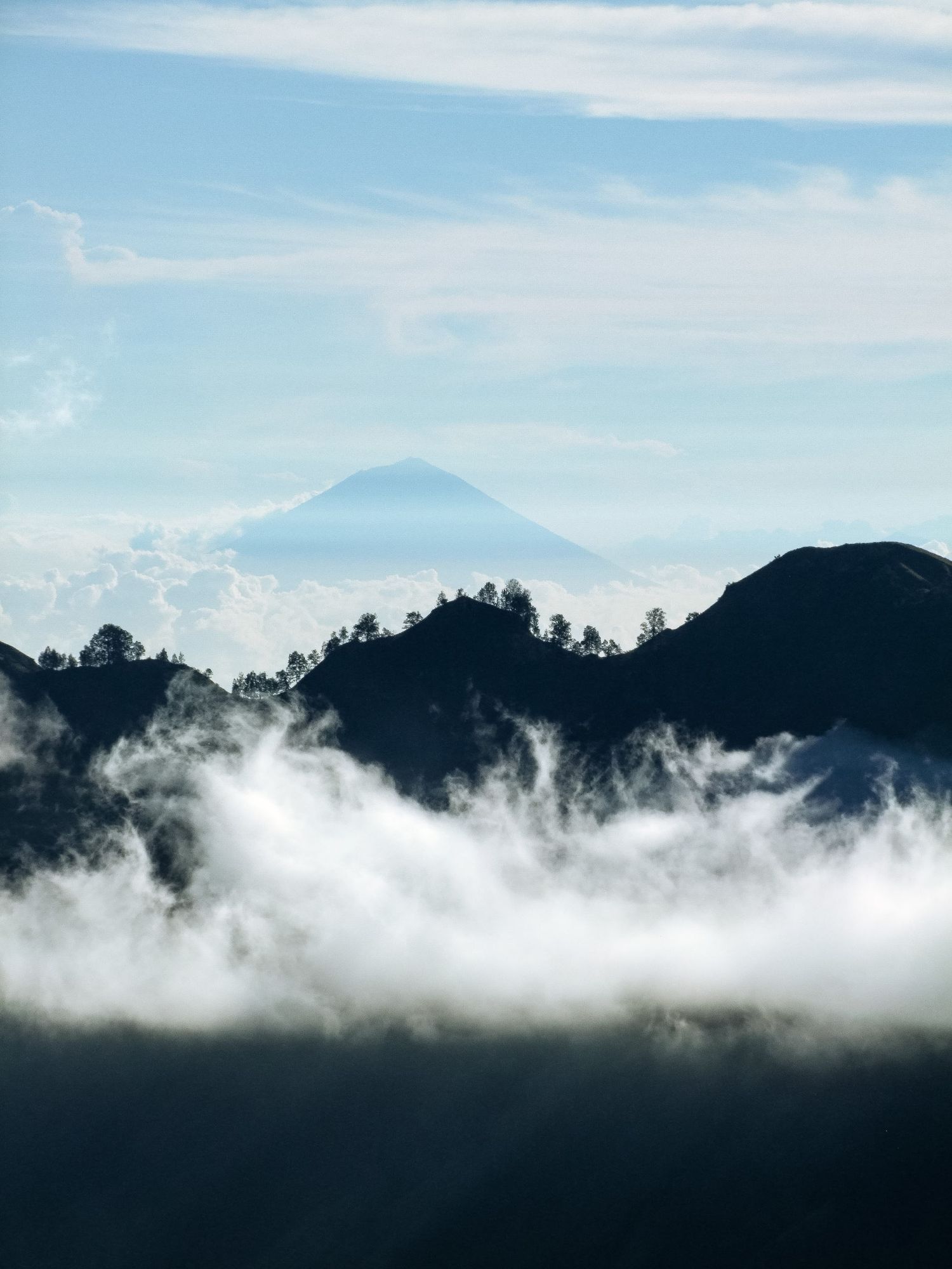 Photographie aérienne en Indonésie montrant le sommet d'un volcan émergeant au-dessus d'une mer de nuages par Jérémie Botte.