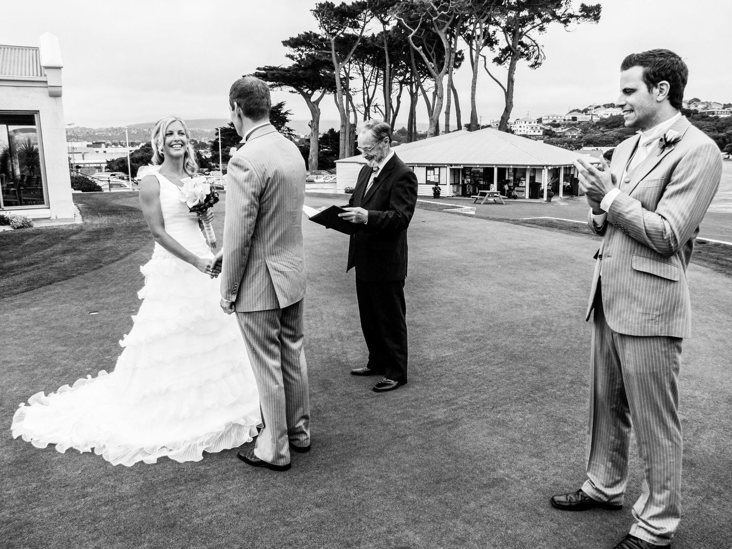 Cérémonie de mariage en extérieur en noir et blanc, les mariés se tenant par la main devant l'officiant, par Jérémie Botte.