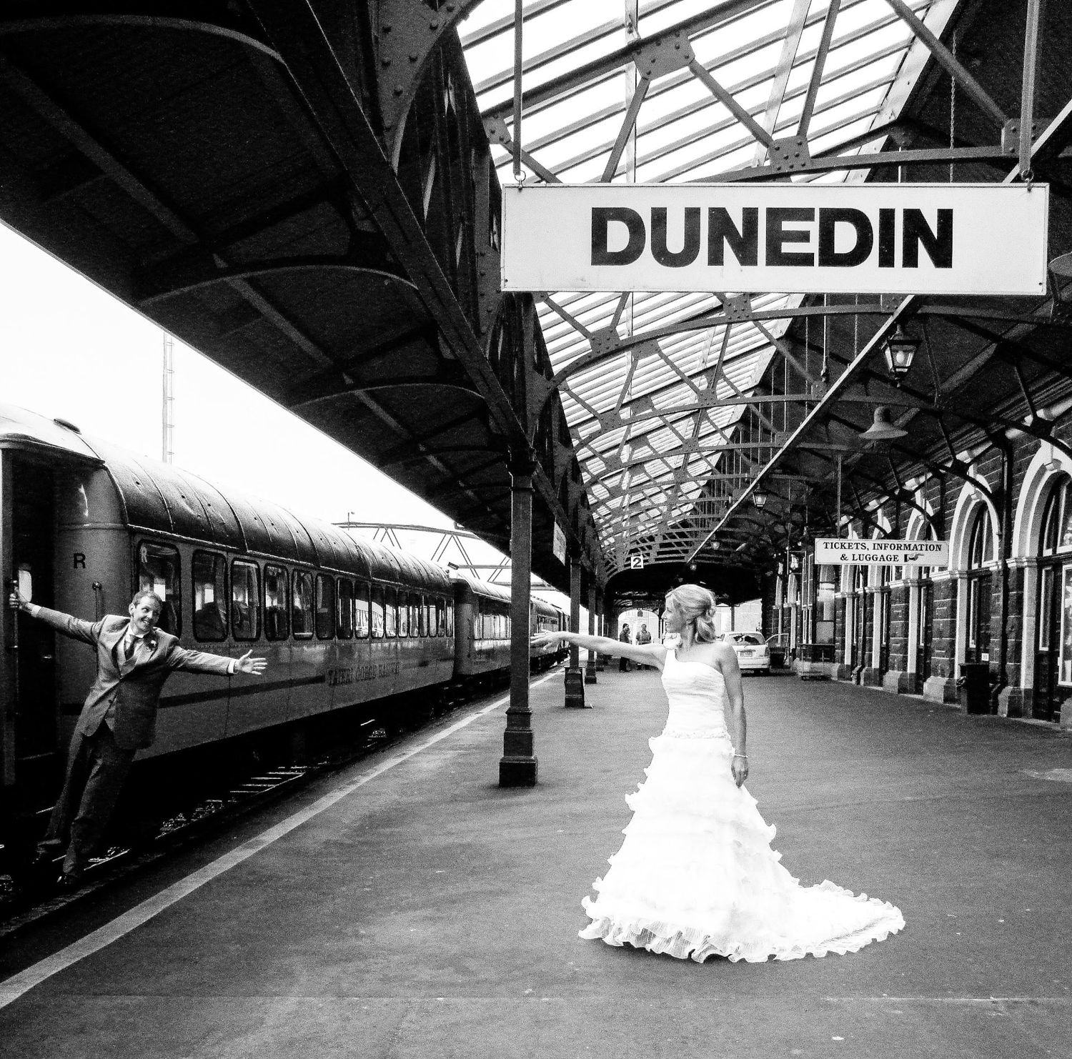Mariés posant sur le quai de la gare de Dunedin, l'époux penché hors d'un train en marche, par Jérémie Botte.