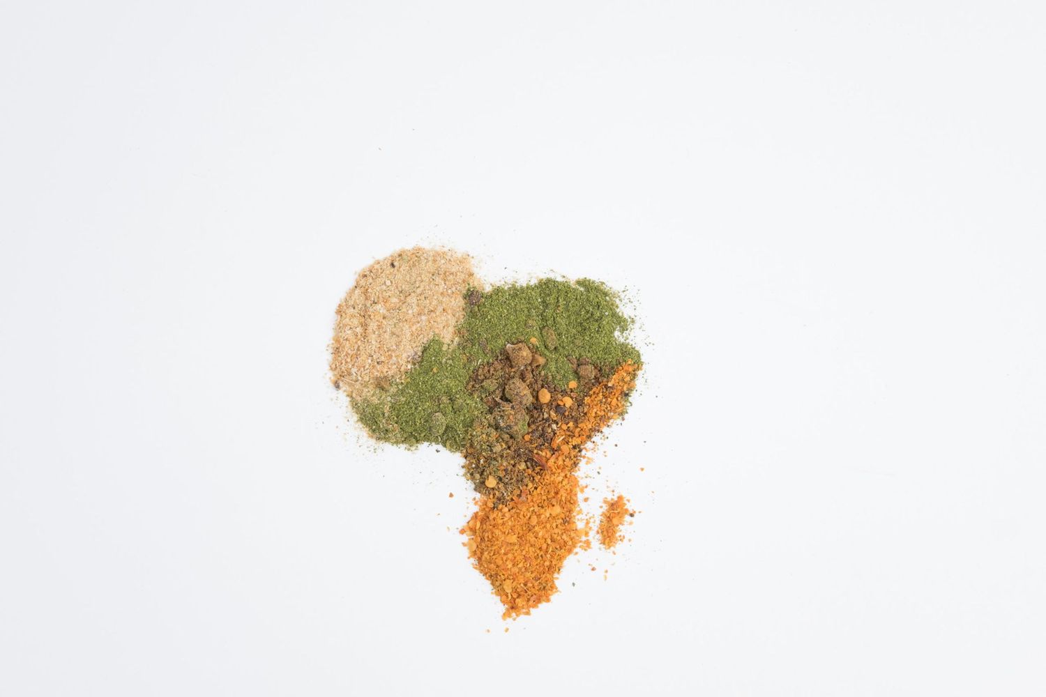 Photographie artistique d'épices colorées formant la carte de l'Afrique sur fond blanc par le photographe Jérémie Botte.