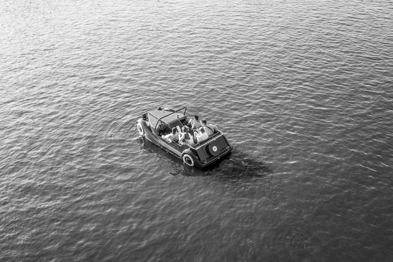 Vue aérienne en noir et blanc d'une voiture décapotable naviguant sur l'eau par Jérémie Botte.