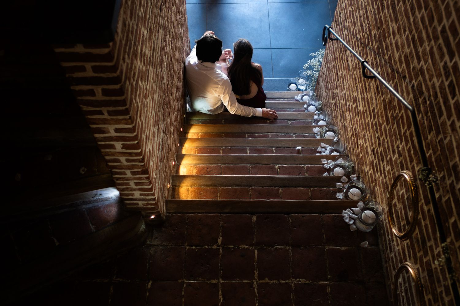 Photographie de mariage en intérieur de deux convives discutant sur des marches d'escaliers par le photographe professionel Jérémie Botte.
