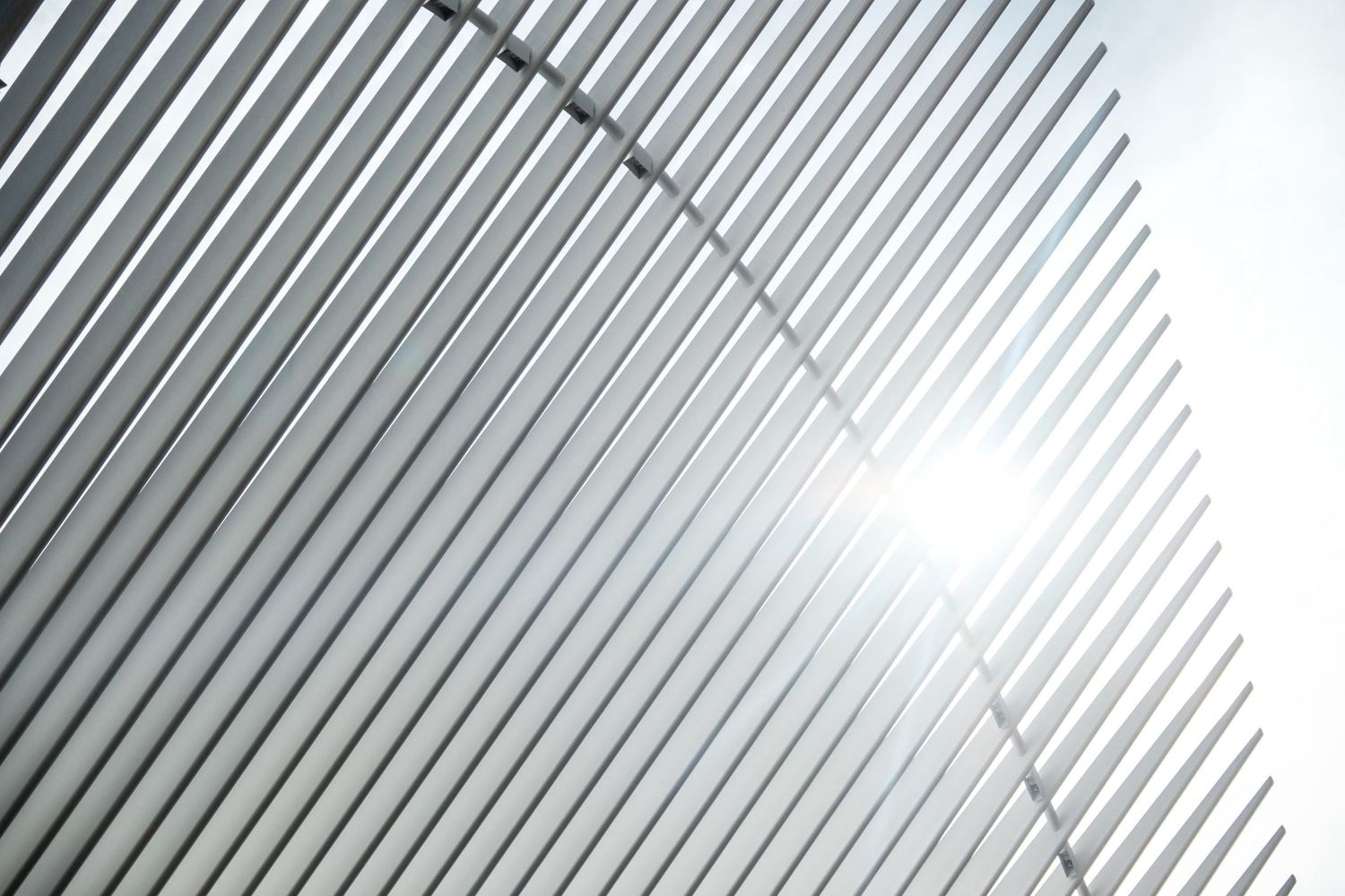 Le soleil brillant  à travers les lignes graphiques et parallèles des structures blanches de l'Oculus à New York, par Jérémie Botte.