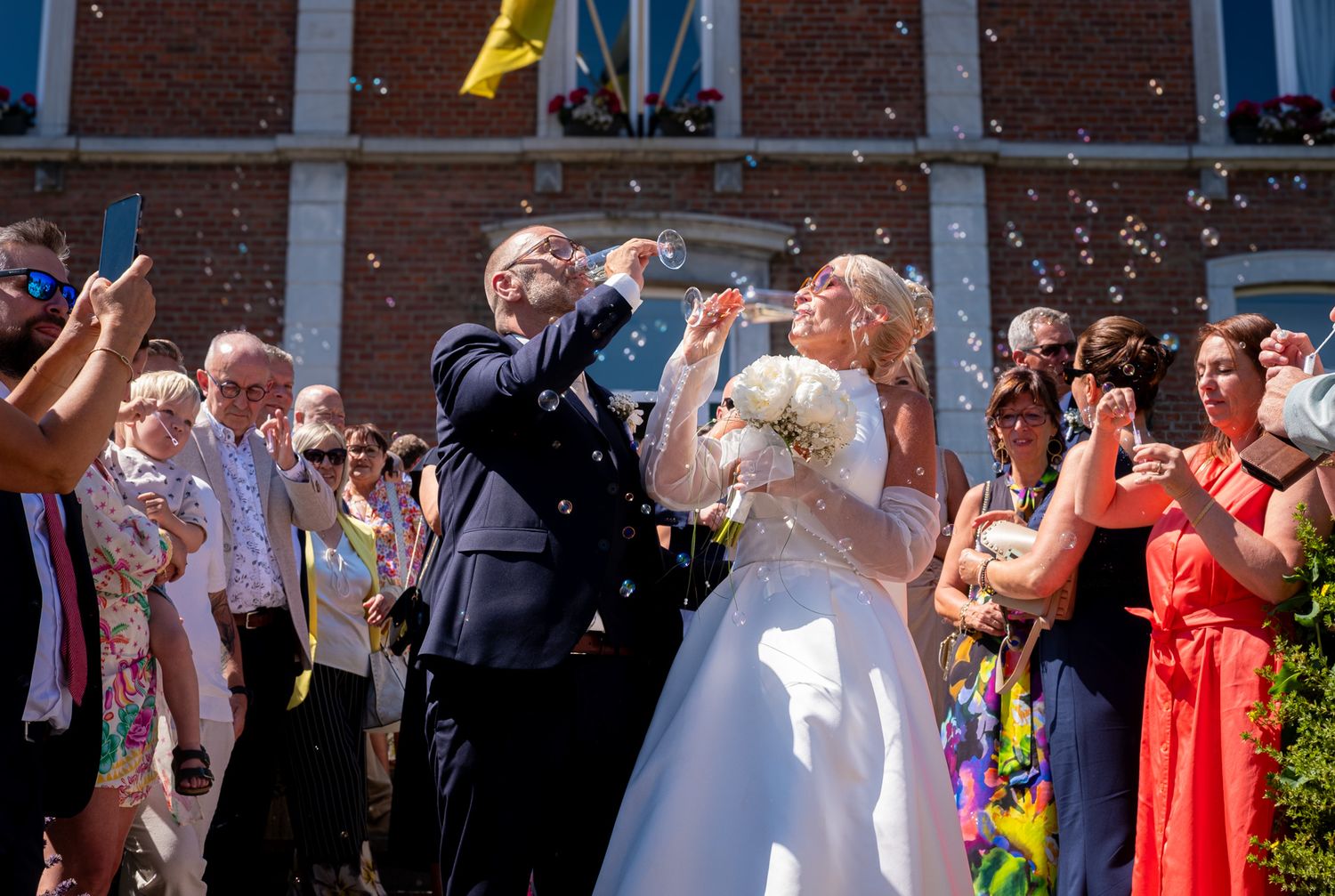 Photographie de mariage en exterieur de jour des deux mariés buvant de champagne par le photographe professionel Jérémie Botte.