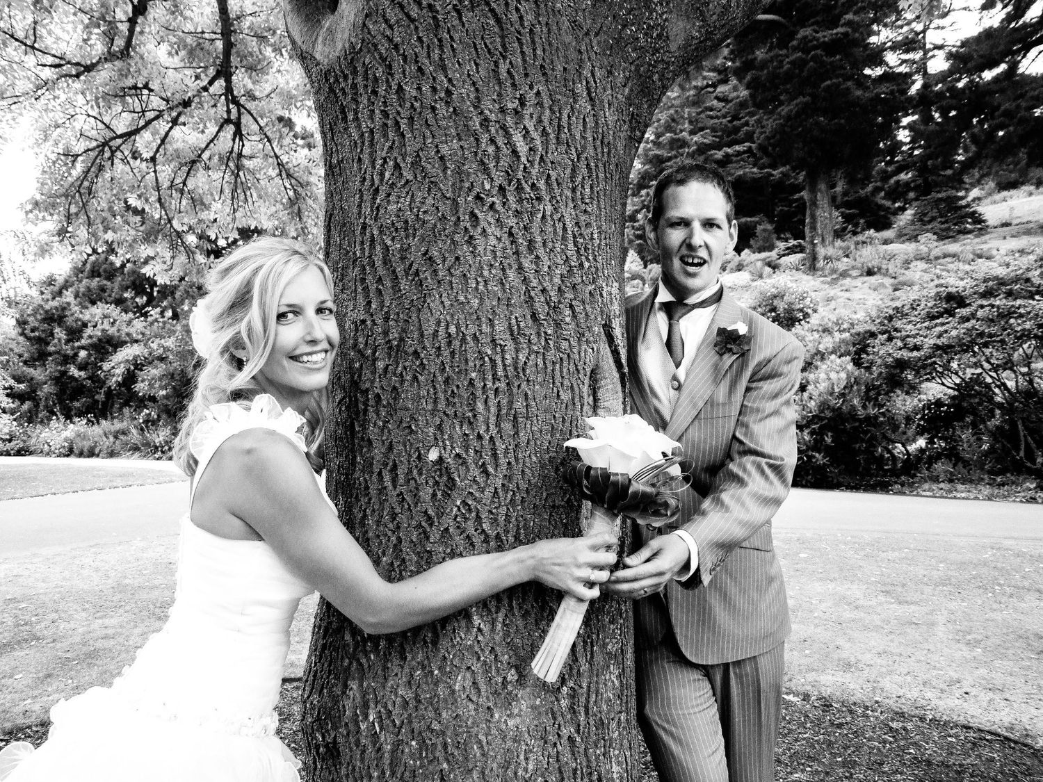 Mariée et marié s'amusant autour d'un grand arbre lors d'une séance photo de mariage, par Jérémie Botte.
