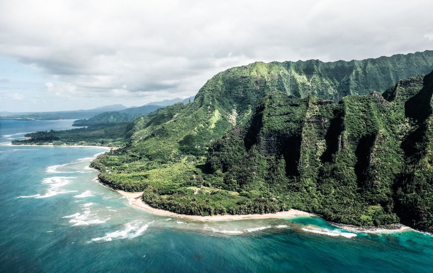 Vue aérienne des falaises verdoyantes de la côte de Na Pali plongeant dans l'océan à Hawaï, par Jérémie Botte.