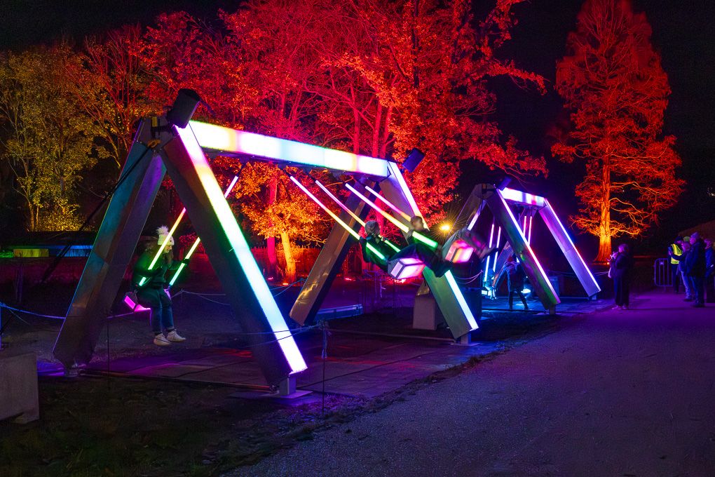 Colourful illuminated installations creating a vibrant nighttime display in the wooded areas of Glow at RHS Bridgewater.