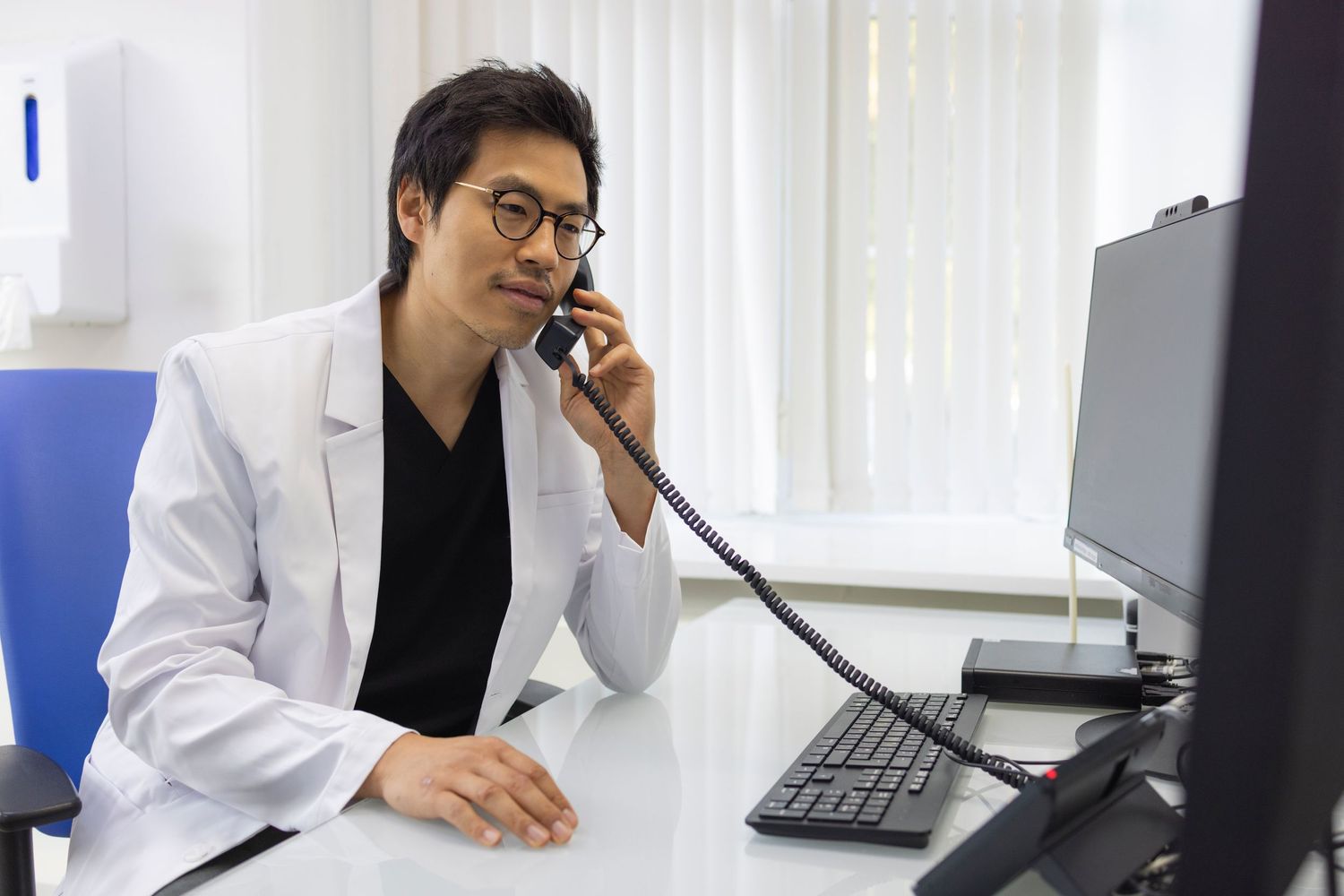 Professional portrait of doctor in medical office speaking on the phone, photographed for healthcare branding and corporate marketing.