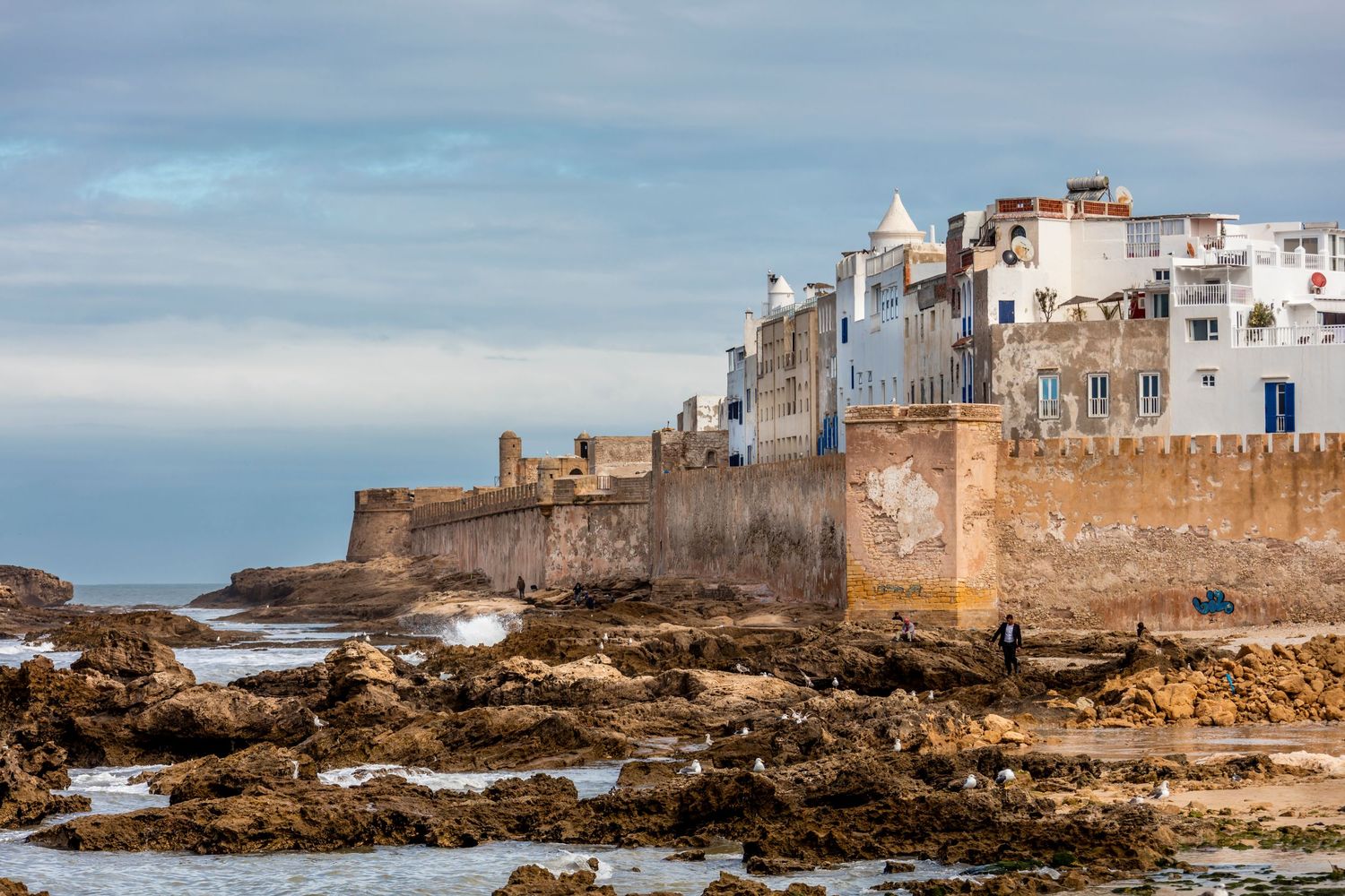 Ancient coastal fortress walls of Essaouira, Morocco, with white medina buildings rising above rocky Atlantic shoreline.